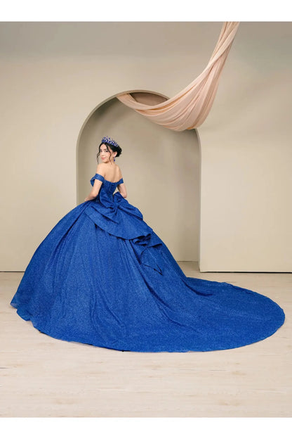 Woman standing side-facing in royal blue ball gown with sparkling beaded corset and flowing glitter tulle skirt

