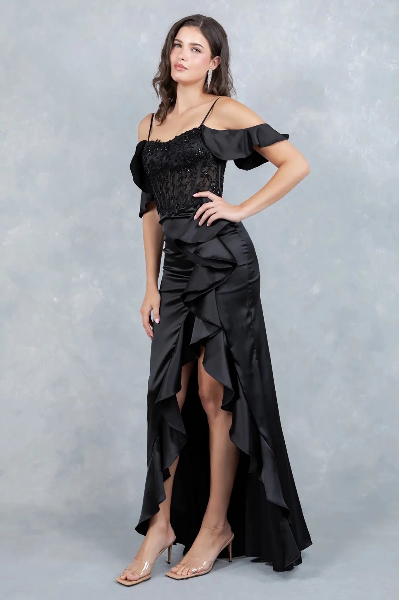 A full-length view of a woman wearing black formal dress with a fitted silhouette and flowing train.