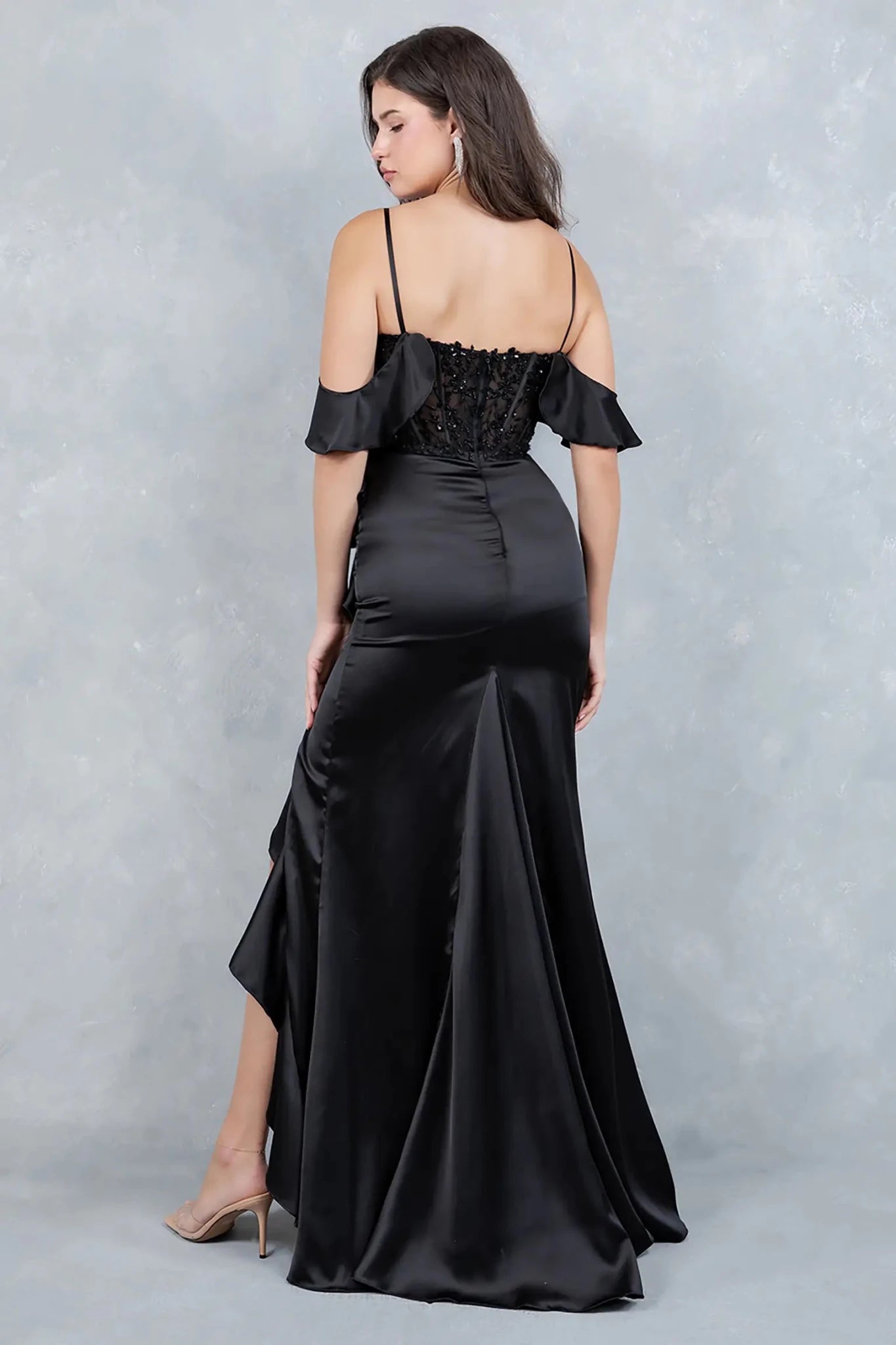 A full back view of a woman wearing a black formal dress with a flowing train and fitted silhouette.