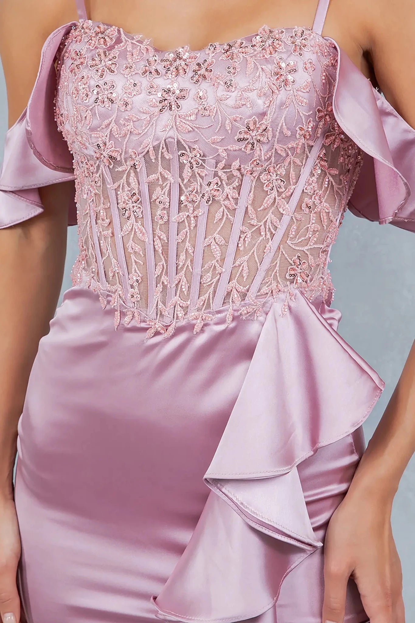 A close-up view of a woman wearing a rose gold lace corset bodice with floral embroidery.