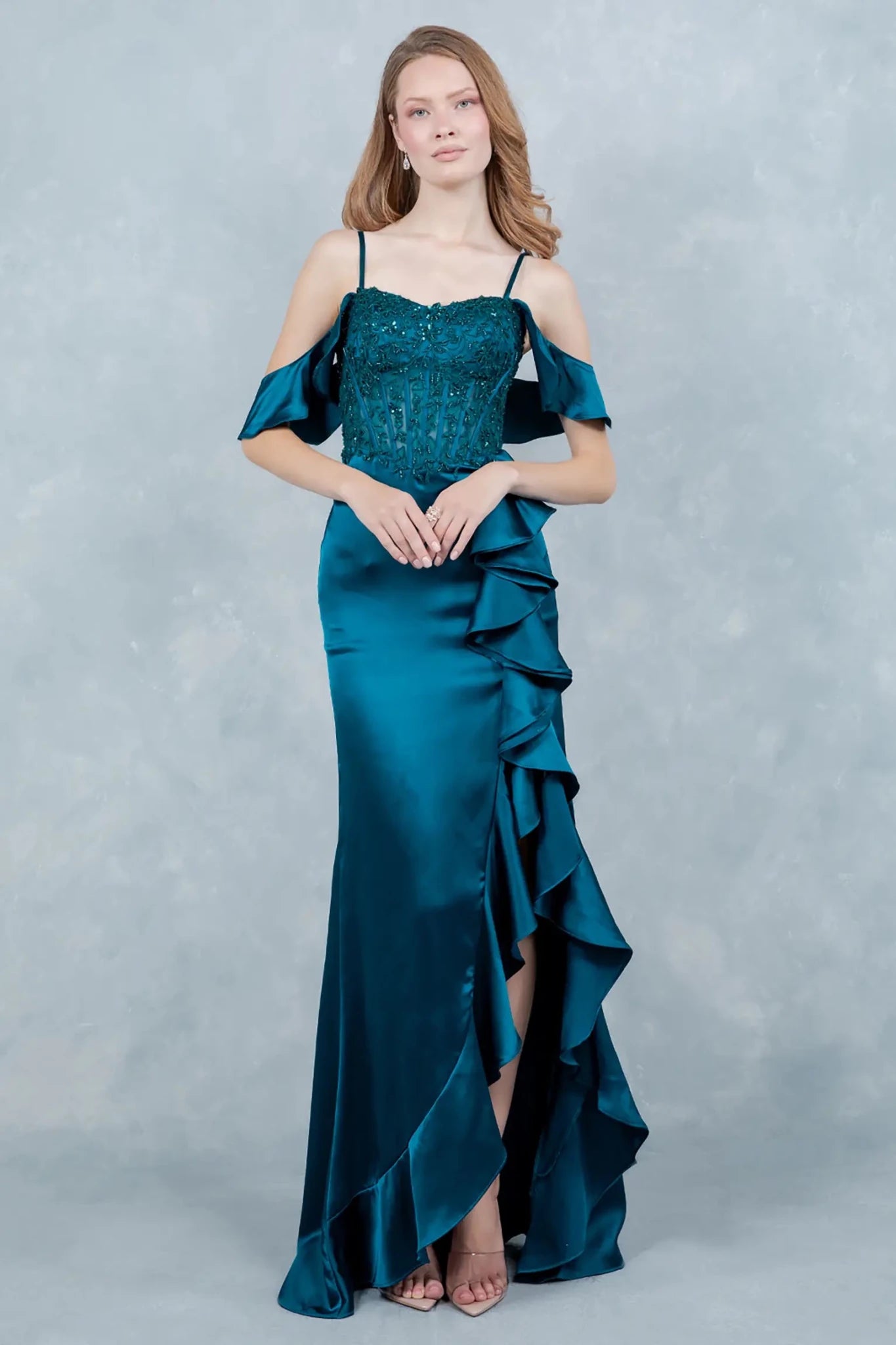 Full front view of a women wearing blue satin prom dress with floral lace corset bodice and ruffle slit.