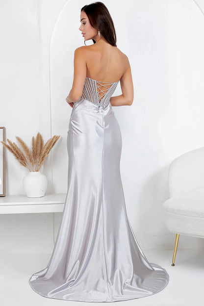 A full back view of a woman wearing a silver formal dress with a lace-up corset and flowing train.