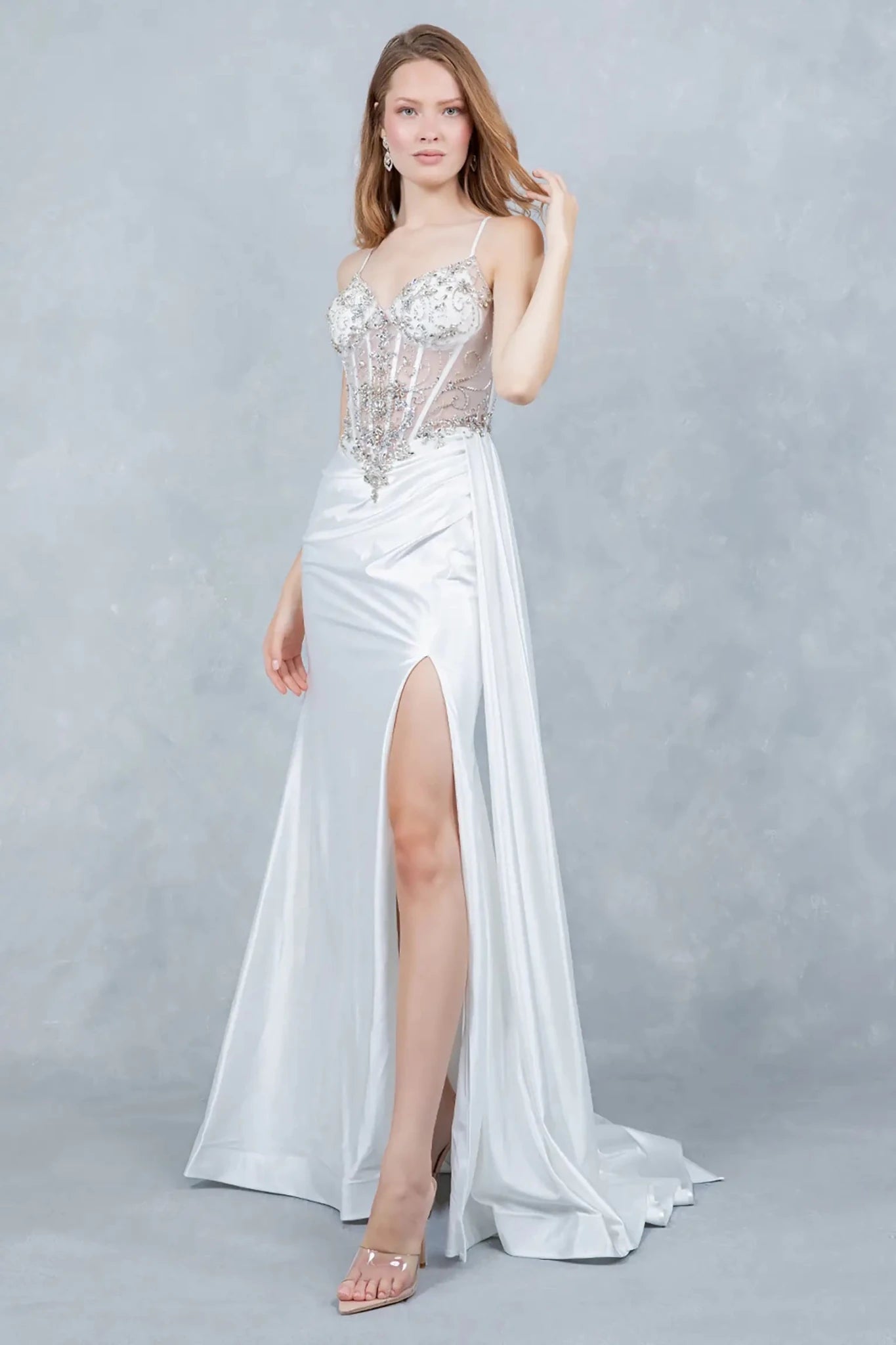 A side profile view of a woman wearing a silver satin prom dress, highlighting the sculpted silhouette and slit.