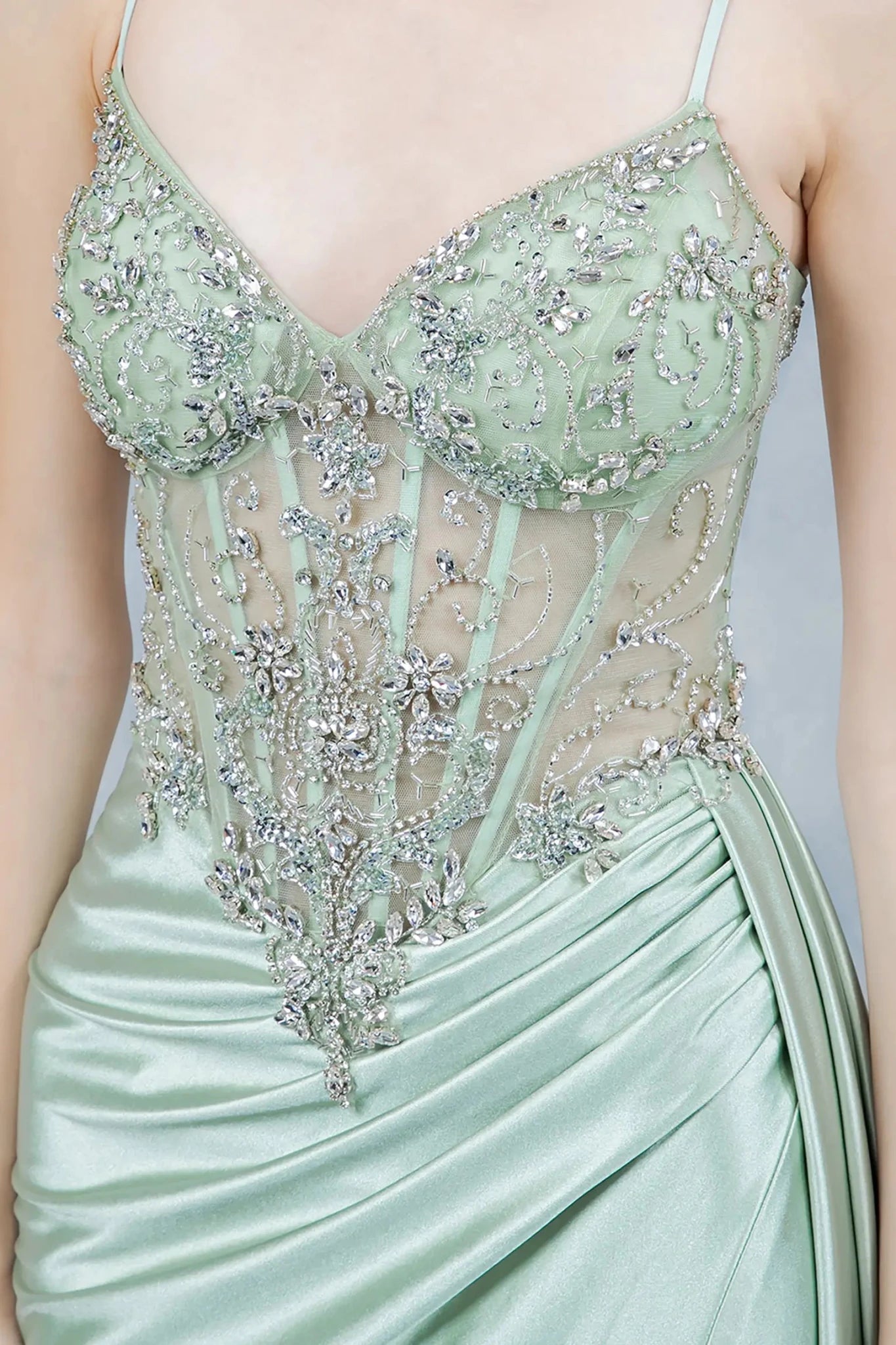 Close-up of sage corset bodice with beadwork, embroidery, and sheer detail.