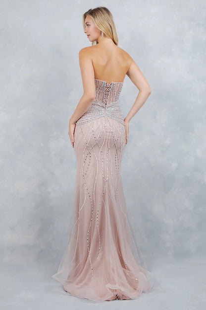 Full-length front view of a woman wearing a blush mermaid prom dress with a lace-up corset bodice and flared tulle hem.