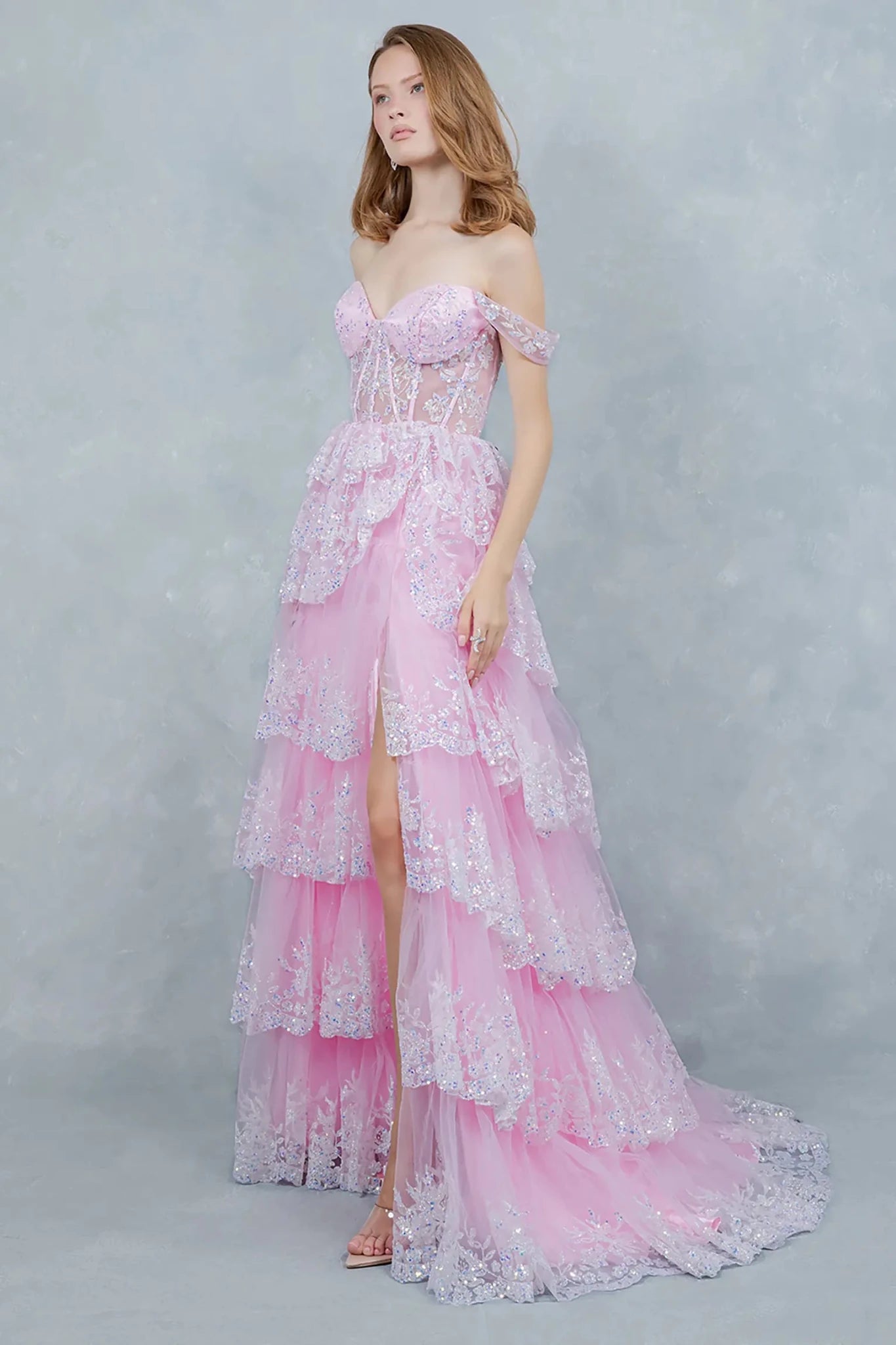A side profile view of a woman wearing a pink glitter prom dress, showcasing the flowing silhouette.