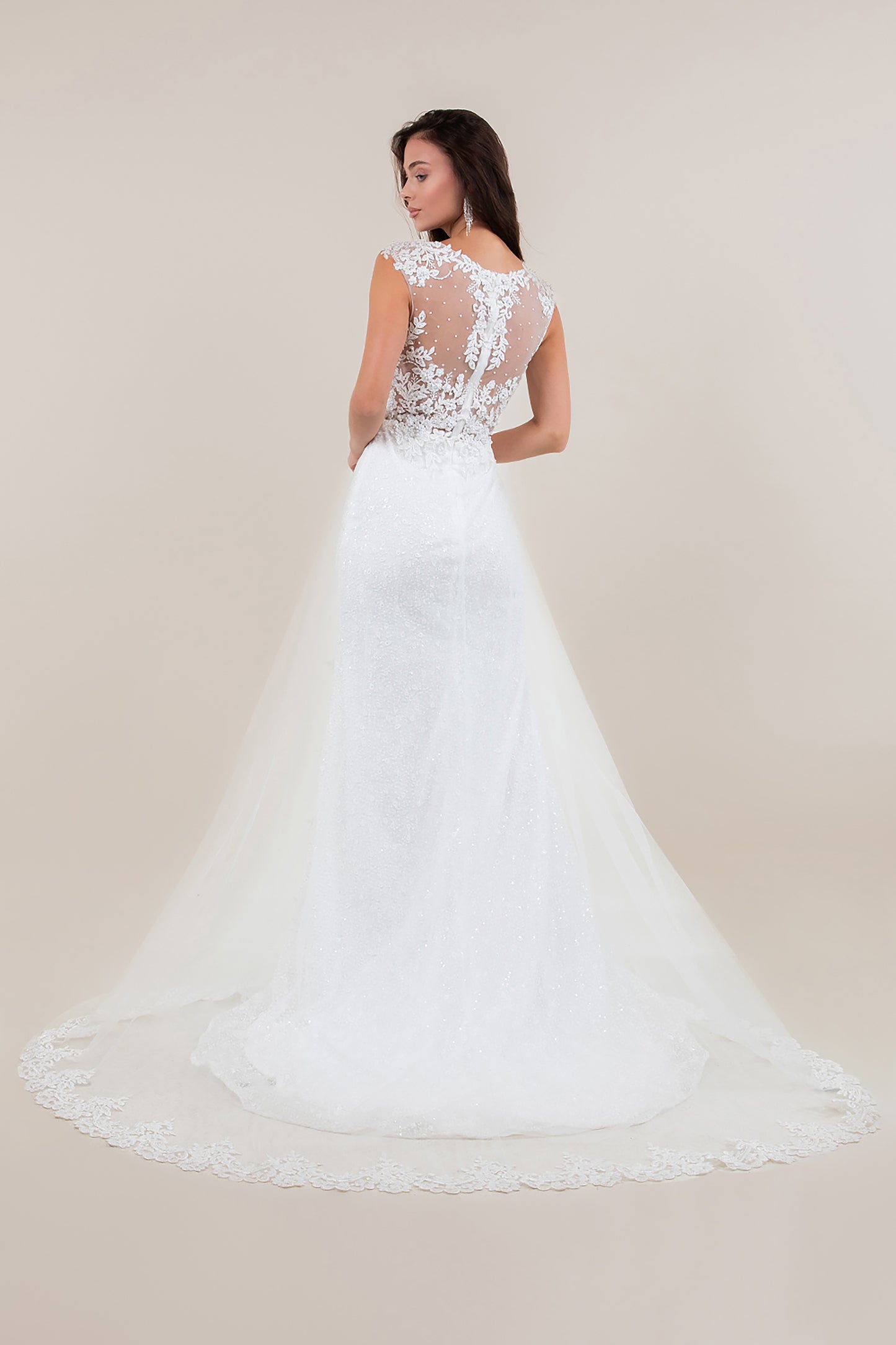 White lace wedding dress with a sheer back on a plain background