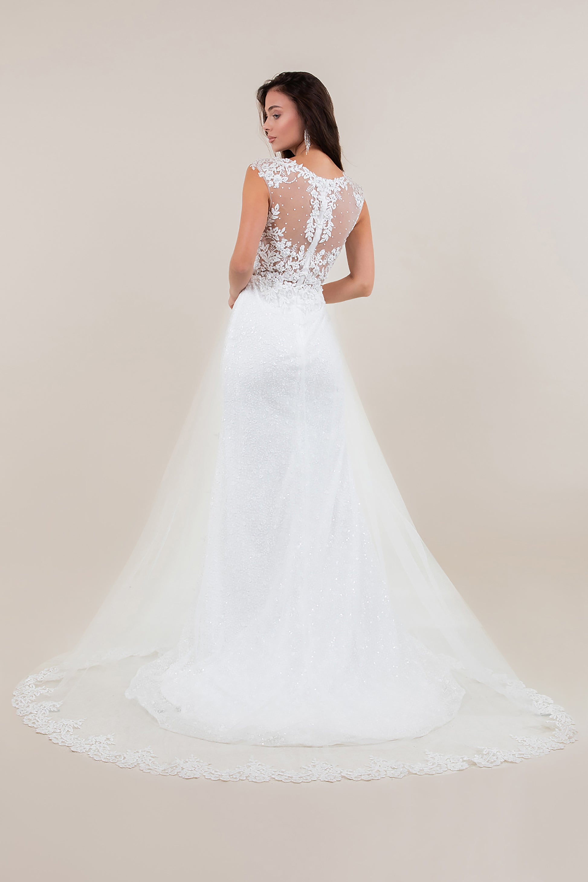 White lace wedding dress with a sheer back on a plain background