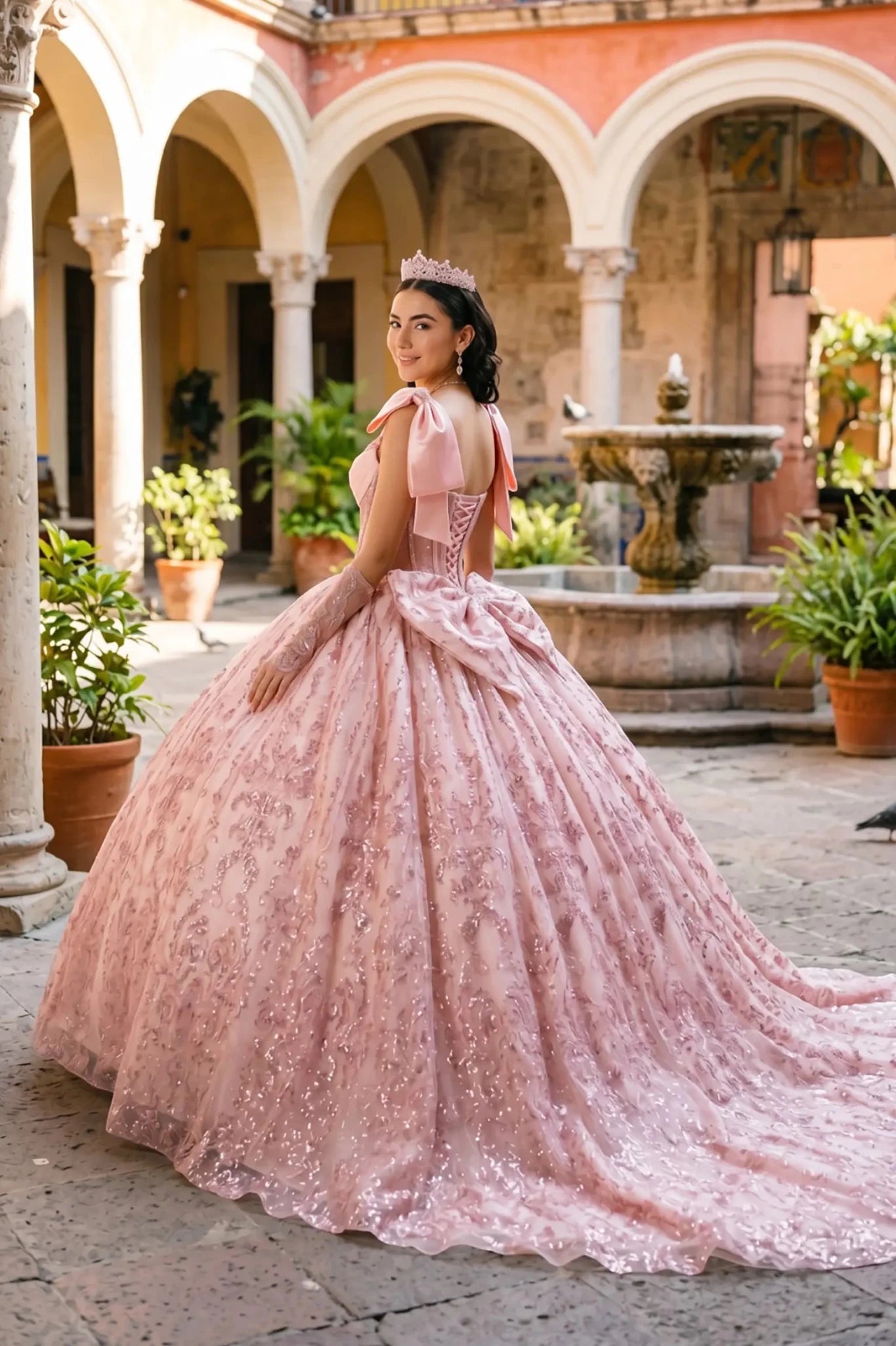 Side view of a woman wearing blush off-shoulder sweetheart quinceañera dress with beaded corset bodice, lace appliqué, and layered tulle skirt