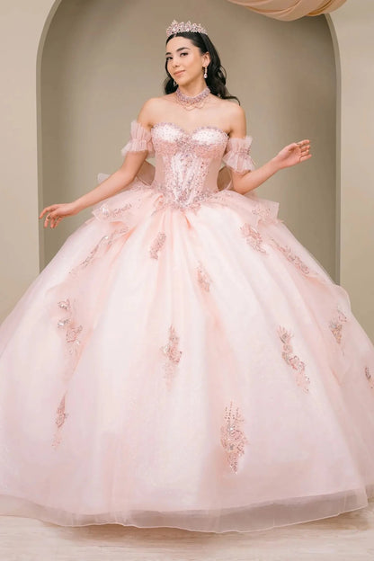 Woman wearing blush off-shoulder sweetheart quinceañera dress with beaded corset bodice, floral appliqué, oversized bow, and flowing train