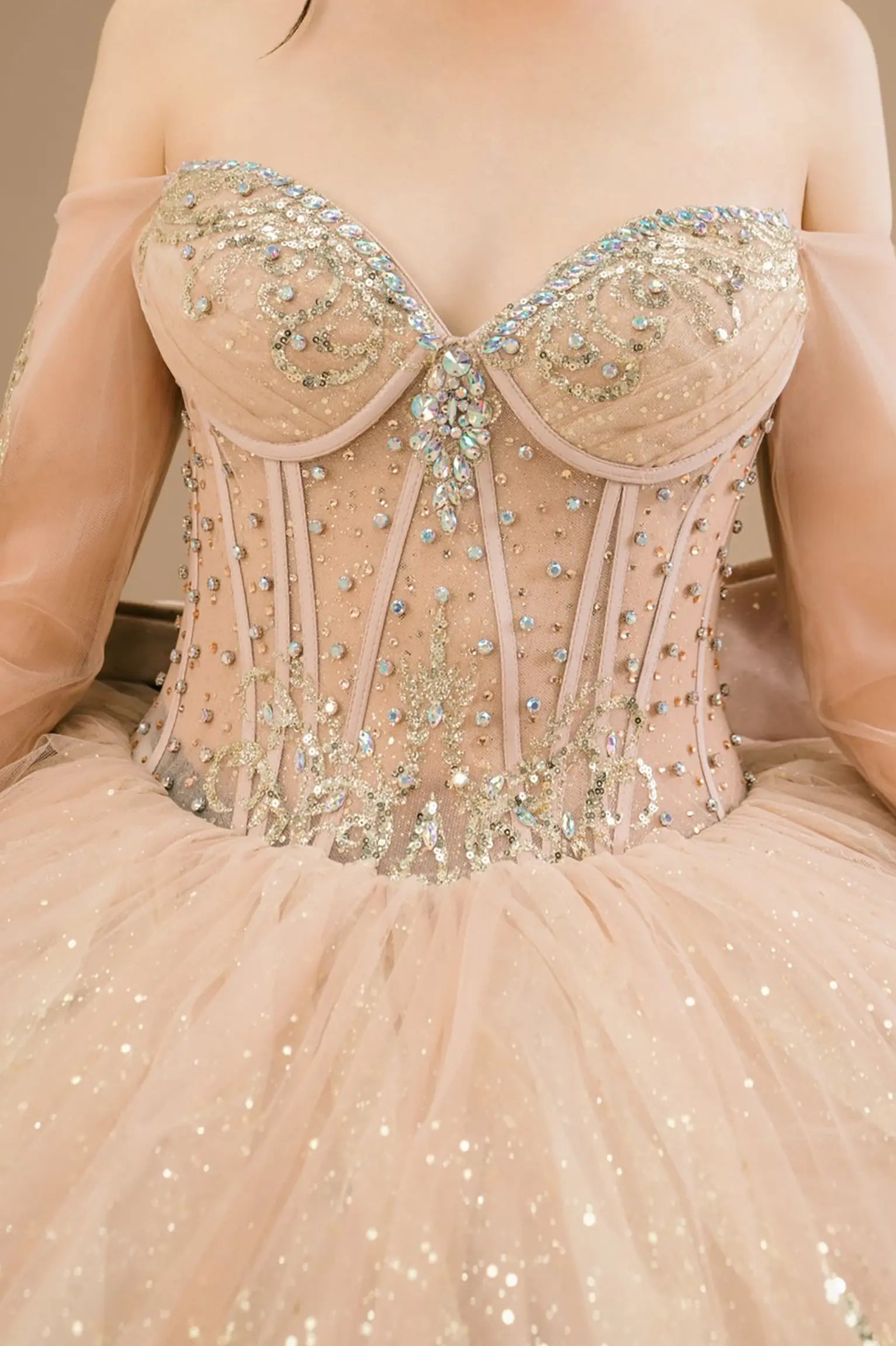 Bodice close-up of a woman wearing mocha quinceañera dress showing intricate gold embroidery, sequins, and beadwork details.