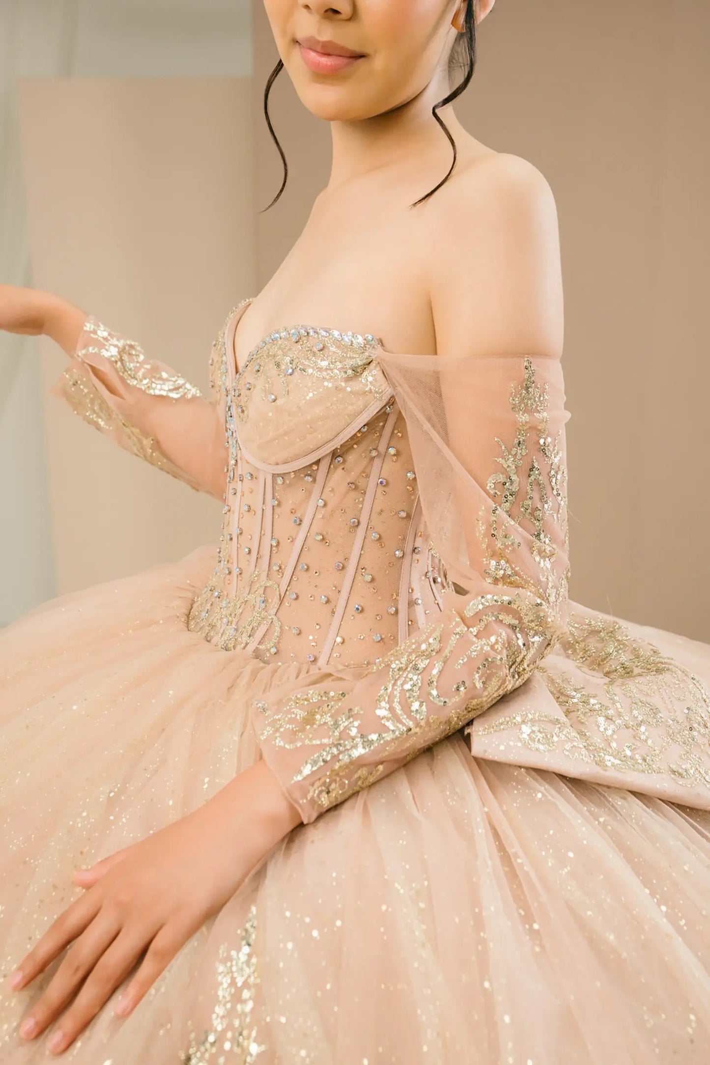 Bodice side close-up of a woman wearing mocha quinceañera dress with gold embroidery, sequins, and lace-up corset design.