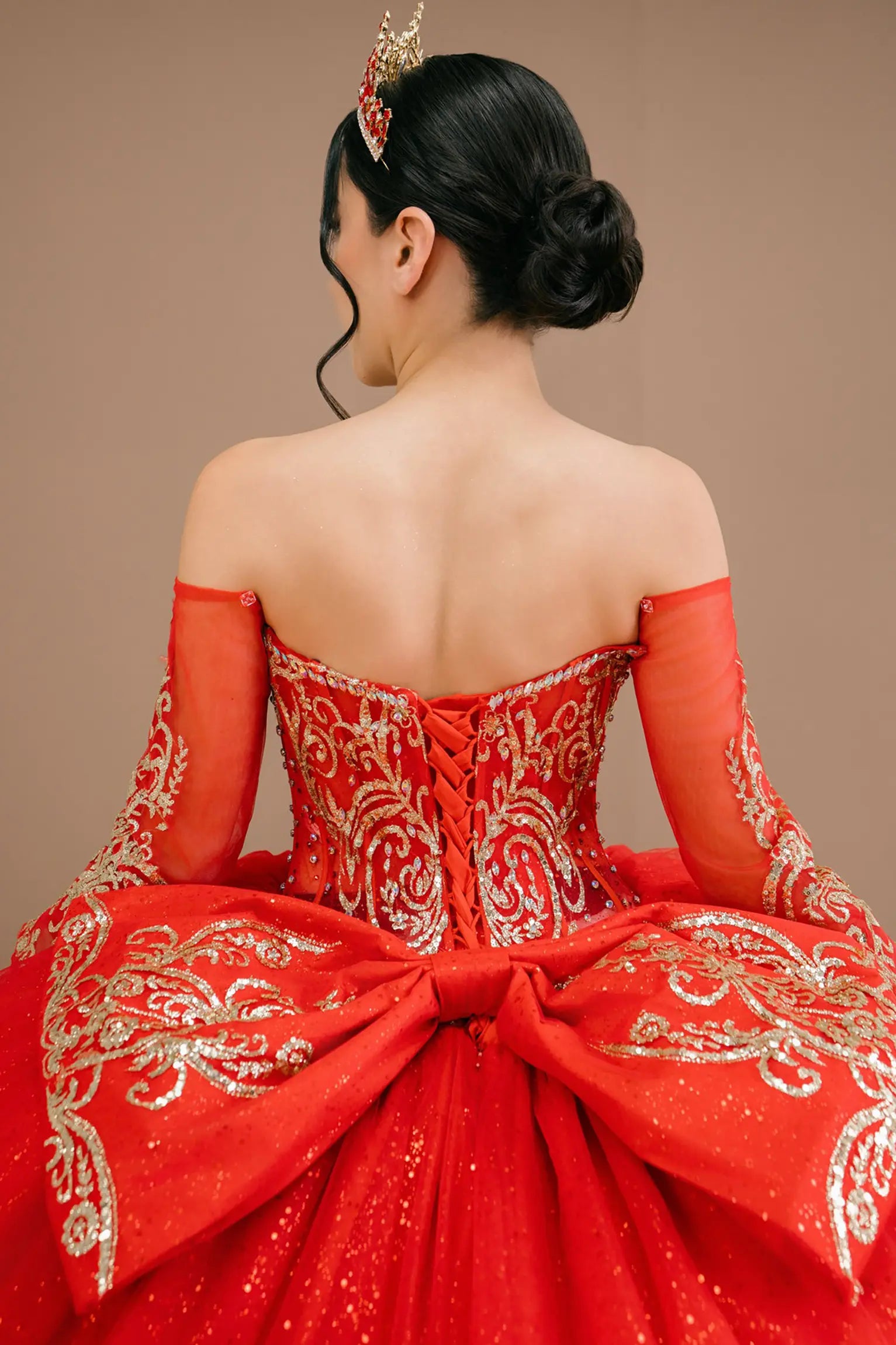 Bodice back close-up of a woman wearing red quinceañera dress with gold embroidery, sequins, and lace-up corset design.