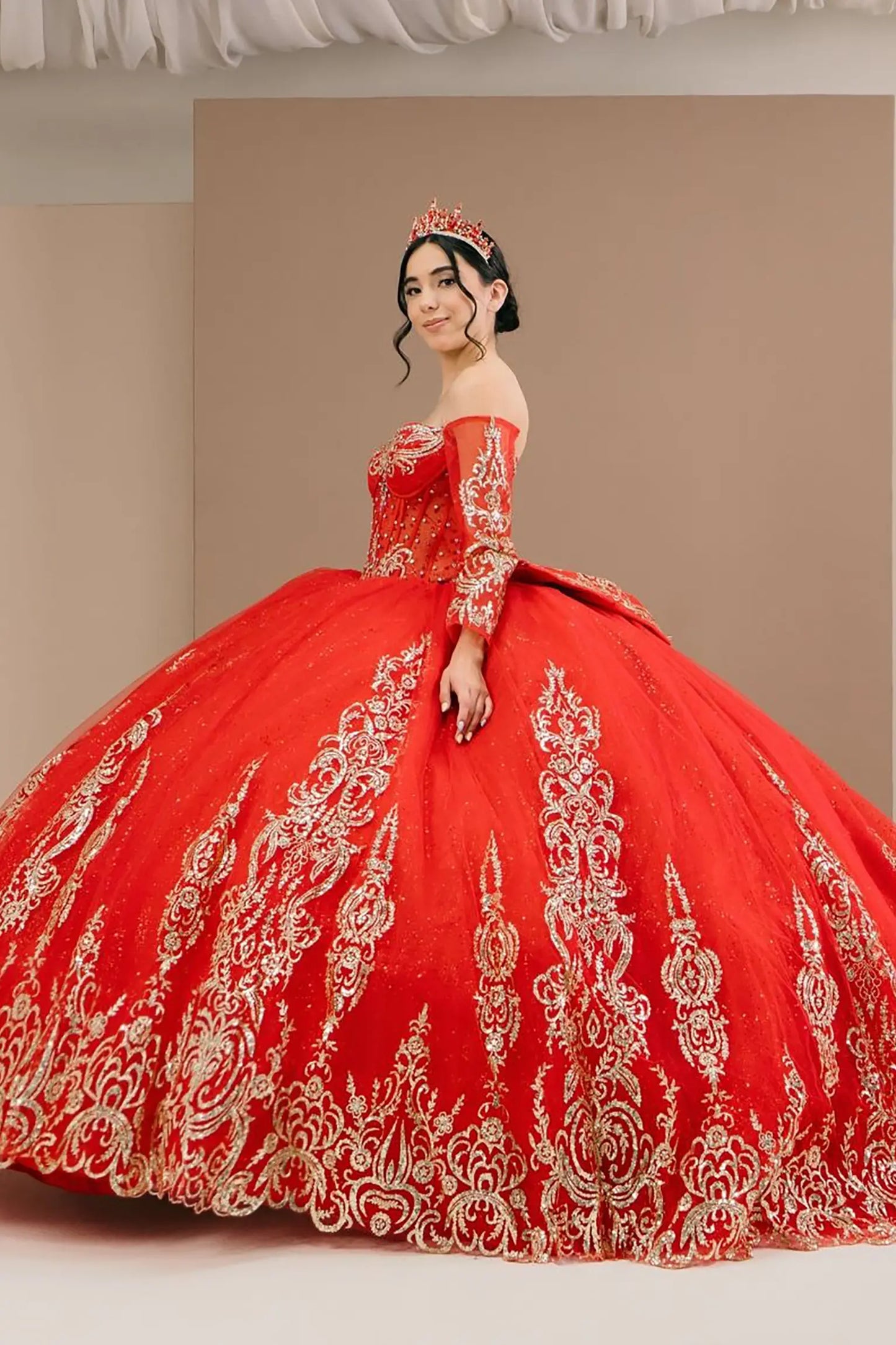 Side close-up view of a woman wearing red quinceañera dress highlighting glitter tulle layers, embroidered bodice, and corset silhouette.