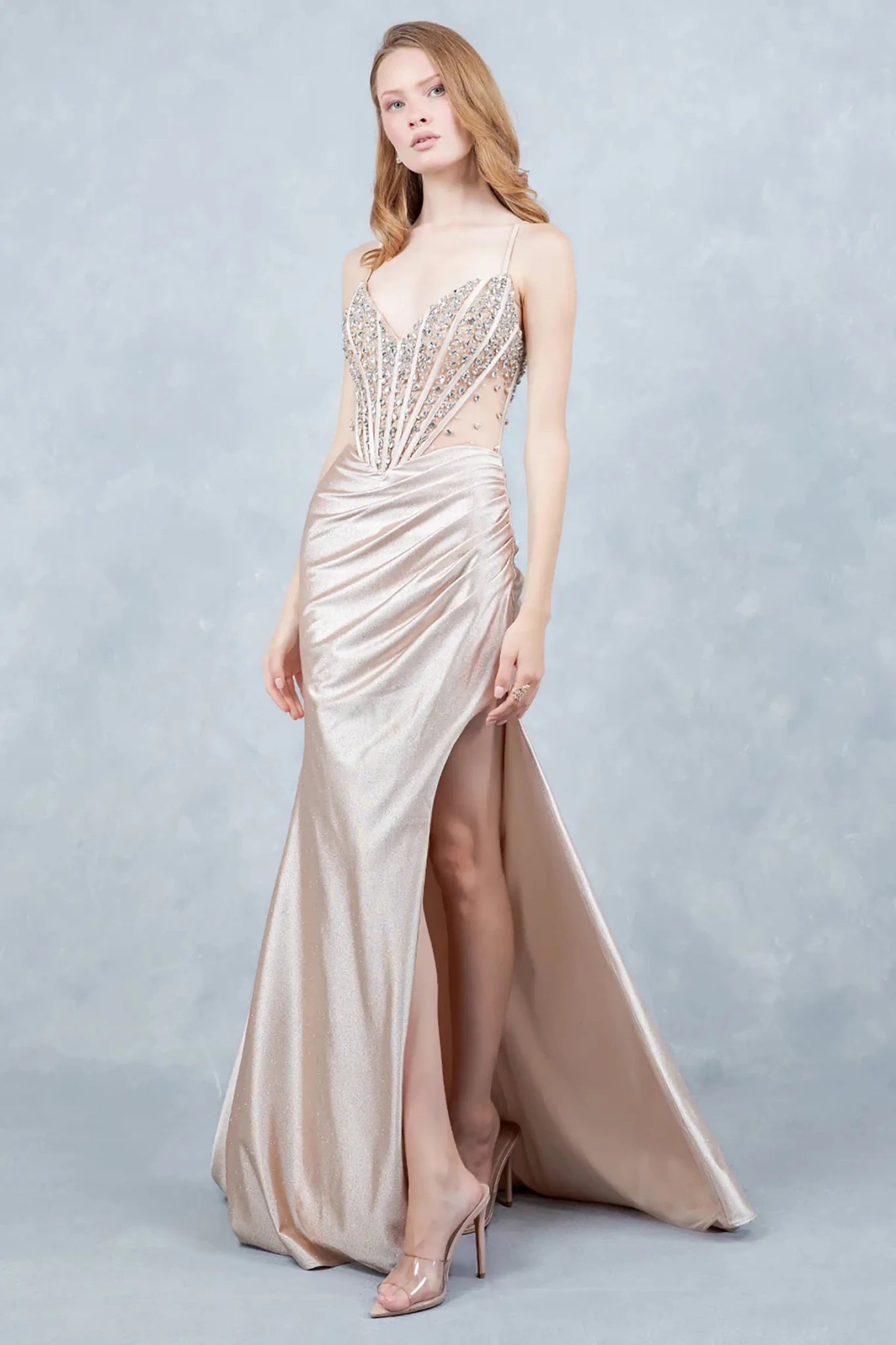 A full-length front view of a woman wearing a champagne glitter prom dress accented with a lace-up corset.
