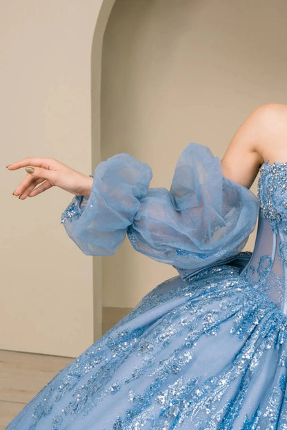 Close-up of woman wearing dusty blue quinceañera dress with voluminous tulle off-shoulder sleeves and beaded sequin bodice