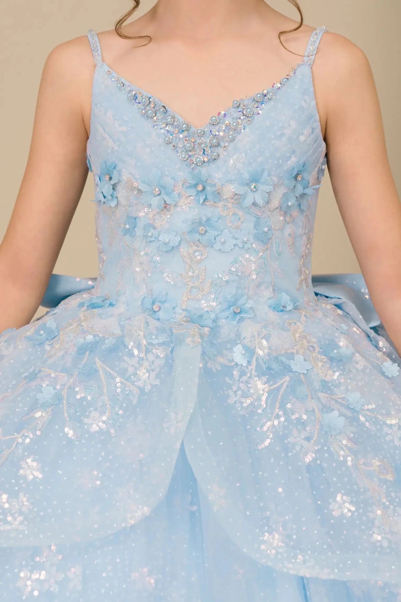 Close-up front-facing view of mini quinceañera ball gown with V-neck corset bodice and sparkling sequin floral embroidery