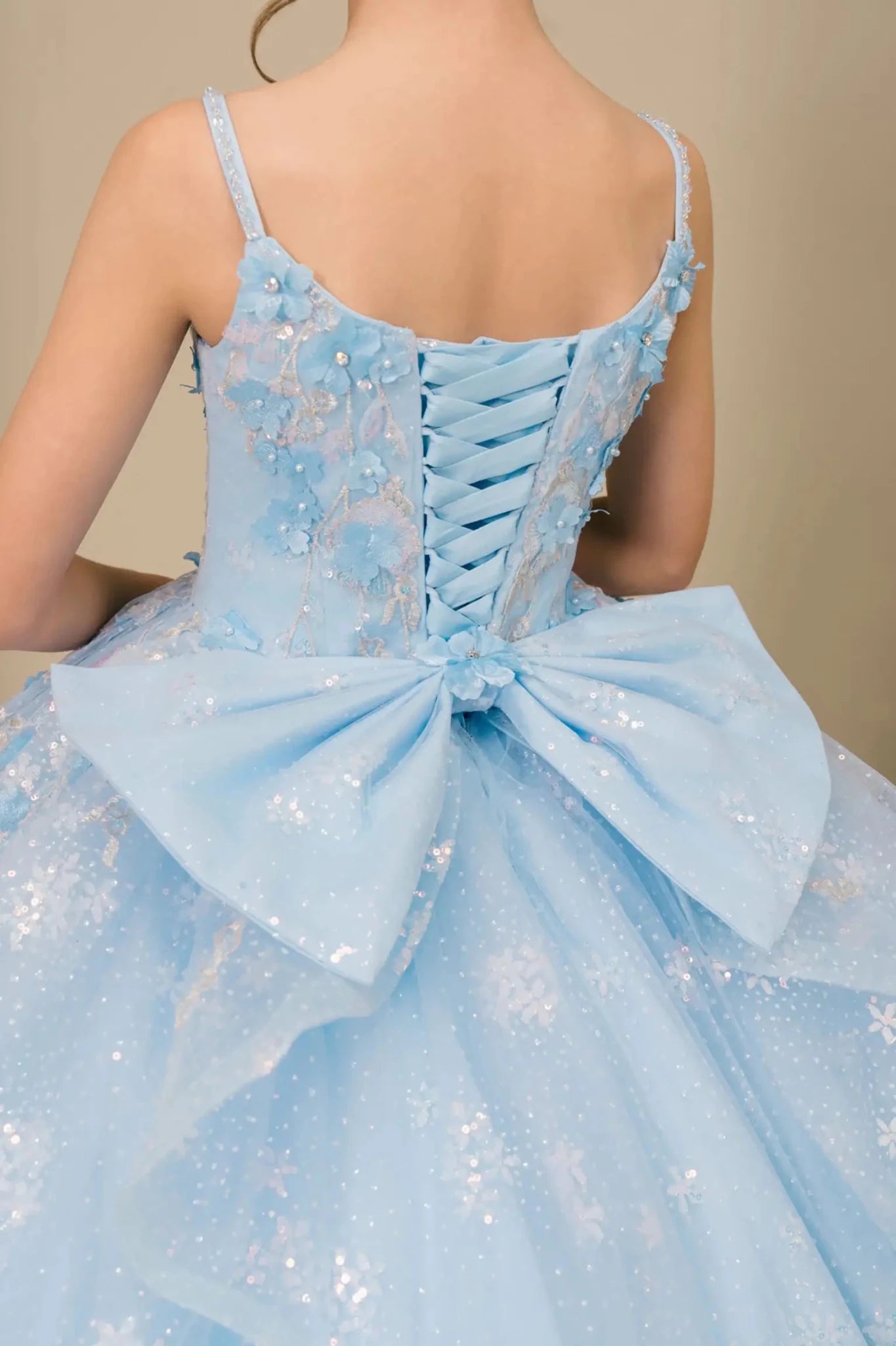 Close-up of mini quinceañera ball gown fabric with sequin floral embroidery and shimmering tulle layers and lace back up