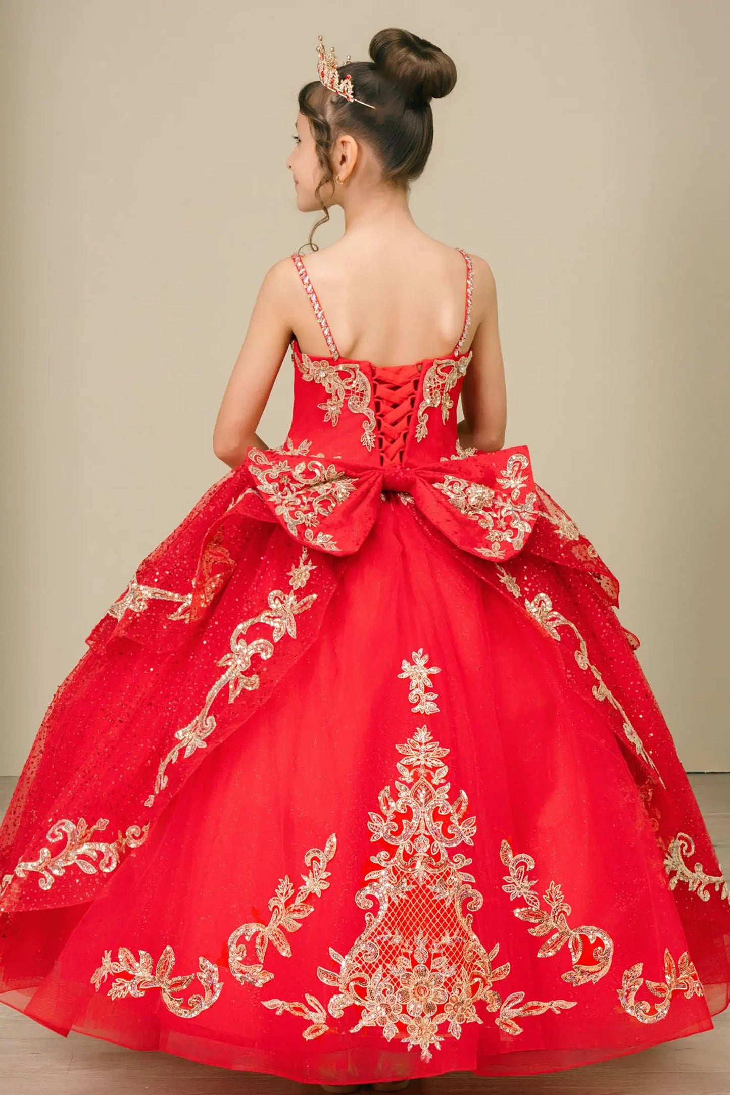 Back view of a red kids quinceañera dress with voluminous layered skirt, lace-up corset closure, and gold embroidered accents.