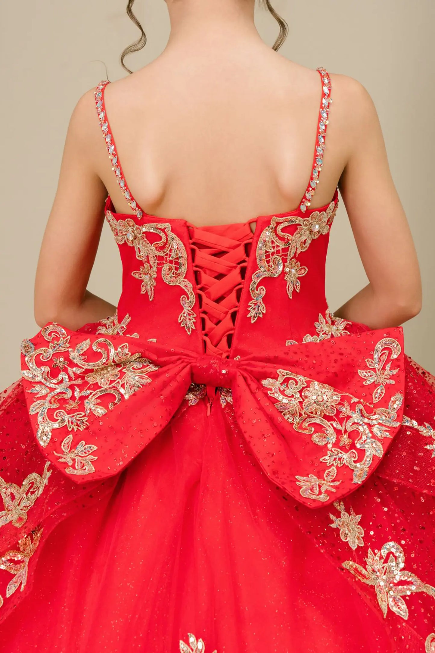Bodice back close-up of a red kids quinceañera dress with gold embroidery, sequins, and lace-up corset design.