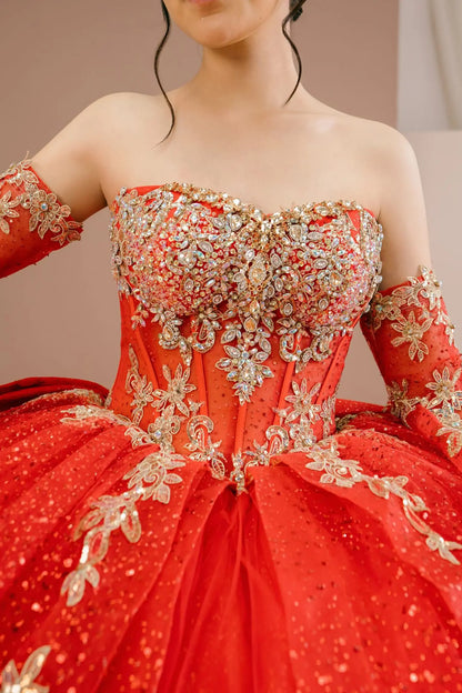 Bodice close-up of a woman wearing red quinceañera dress showing intricate gold embroidery, sequins, and beadwork details with sheer sleeve accents.