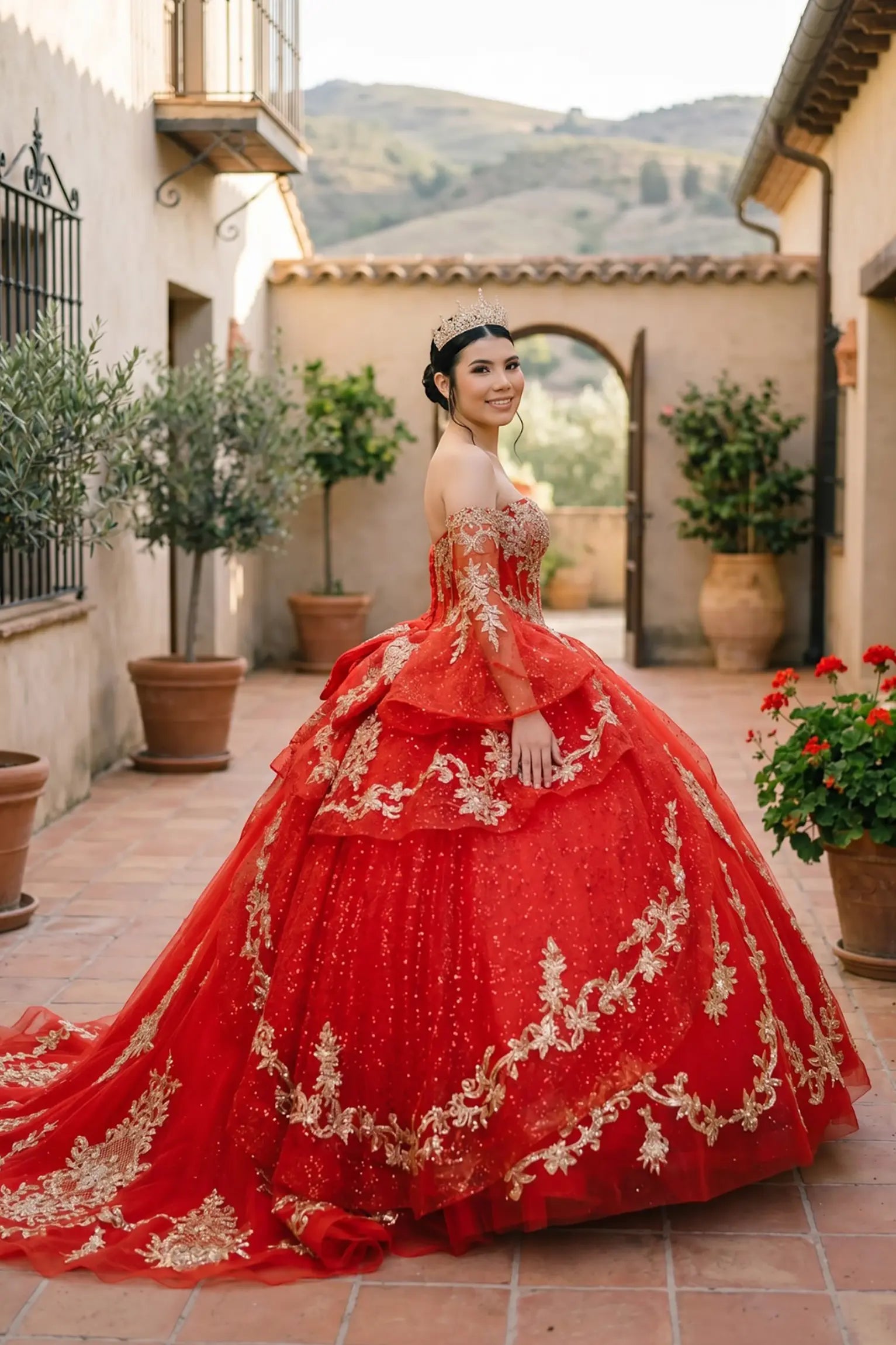 Side close-up view of a woman wearing red quinceañera dress highlighting ethereal sheer sleeves, embroidered bodice, and layered glitter tulle skirt.