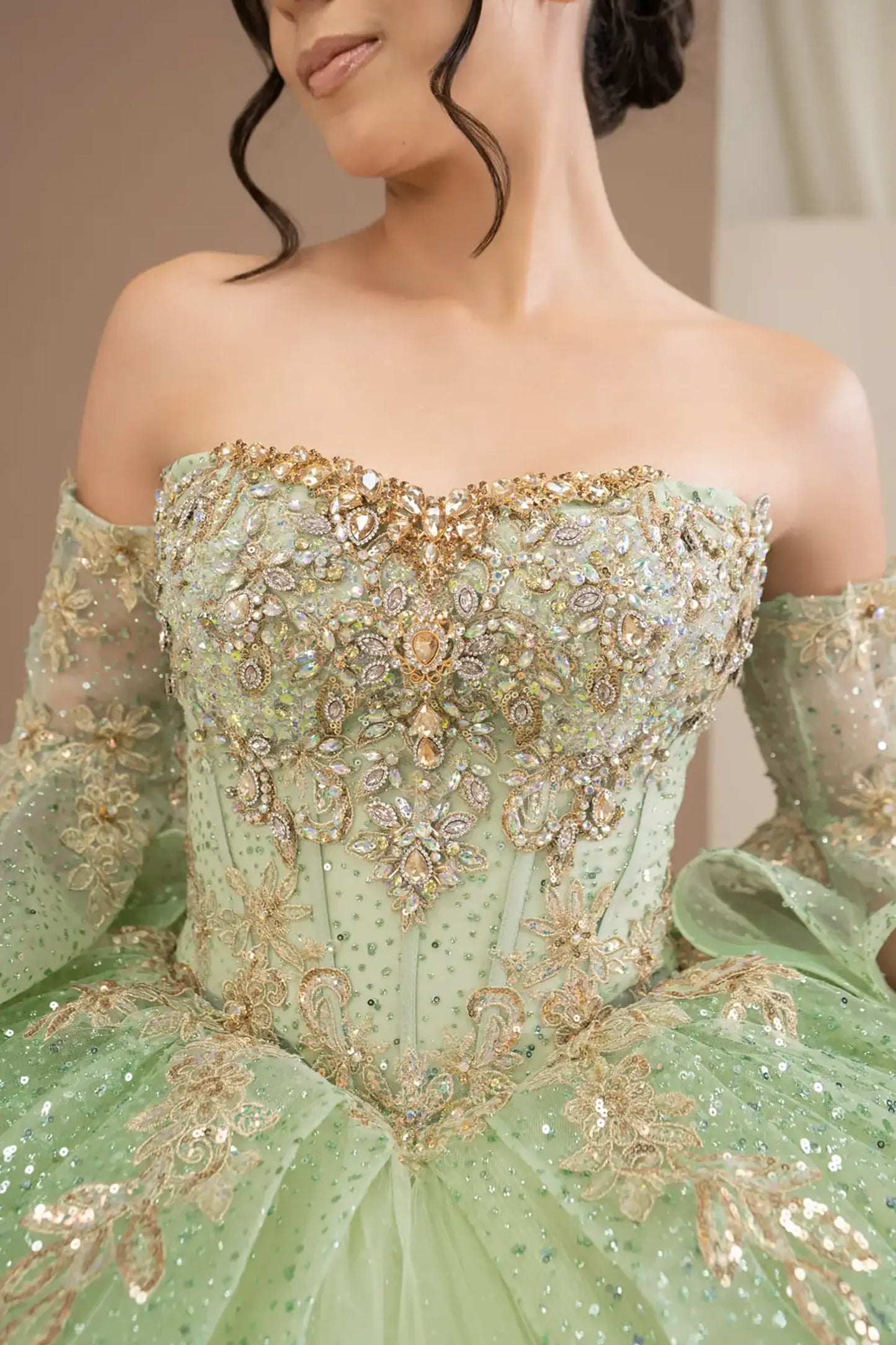 Bodice close-up of a woman wearing sage quinceañera dress showing intricate embroidery, beadwork details, and sparkling sequins.