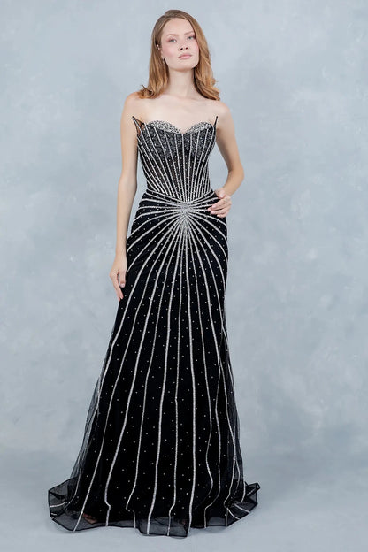 A full-length view of a woman wearing black mermaid prom dress with a lace-up corset detail.