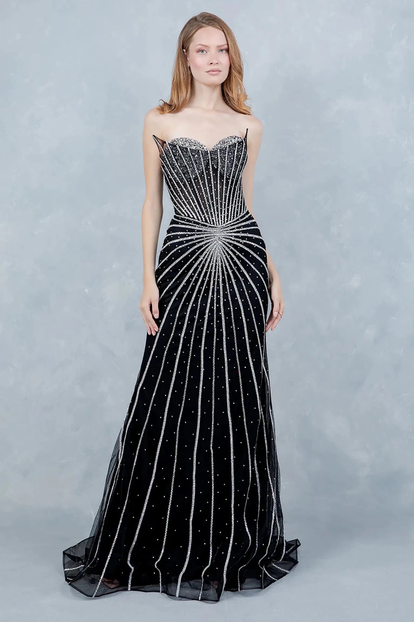 A full-length front view of a woman wearing a black mermaid prom dress featuring a lace-up corset detail.