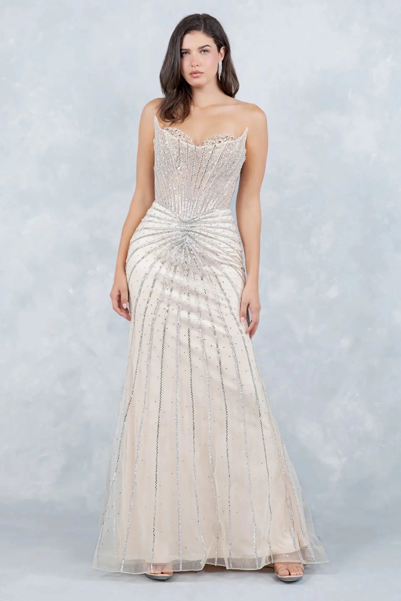 A full-length view of a woman wearing champagne mermaid dress with corset closure.