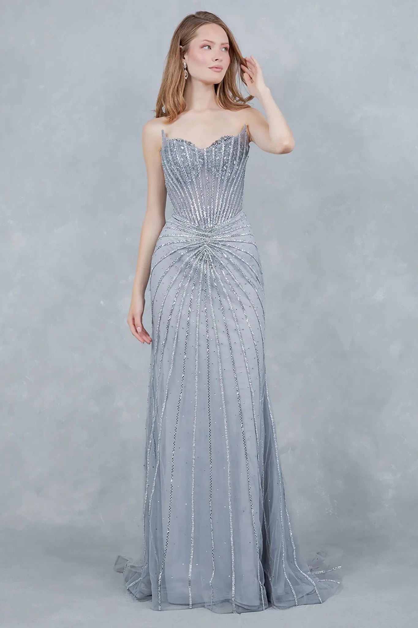 A full-length view of a woman wearing silver formal prom dress with a lace-up corset.