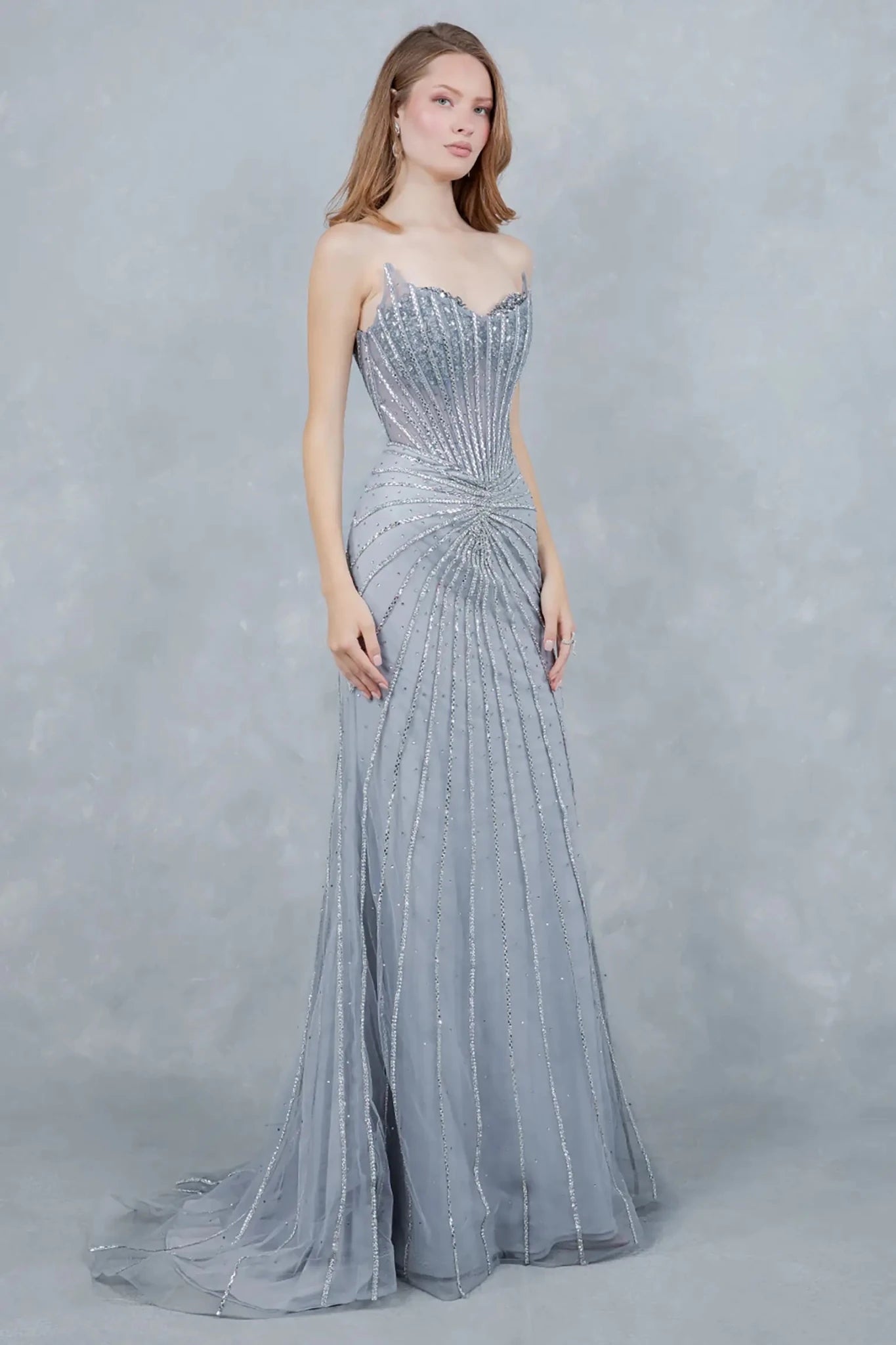 A side profile view of a woman wearing a silver mermaid prom dress, emphasizing the fitted elegance.