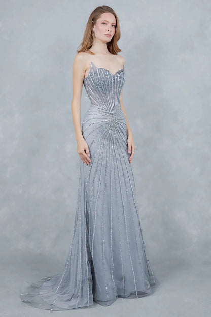 A side profile view of a woman wearing a silver mermaid prom dress, emphasizing the fitted elegance.