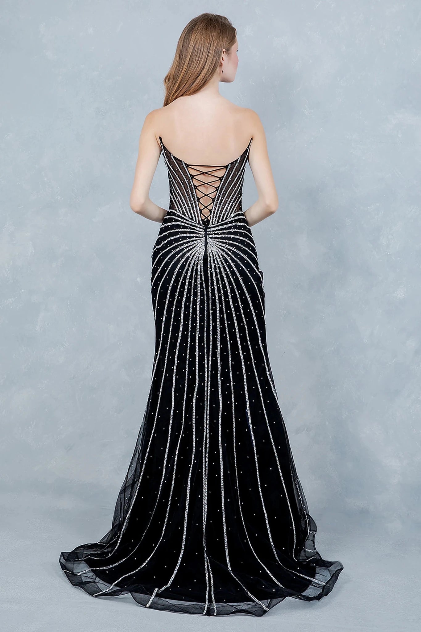 Black evening gown showcasing sunburst pattern extending across structured bodice and lace back up