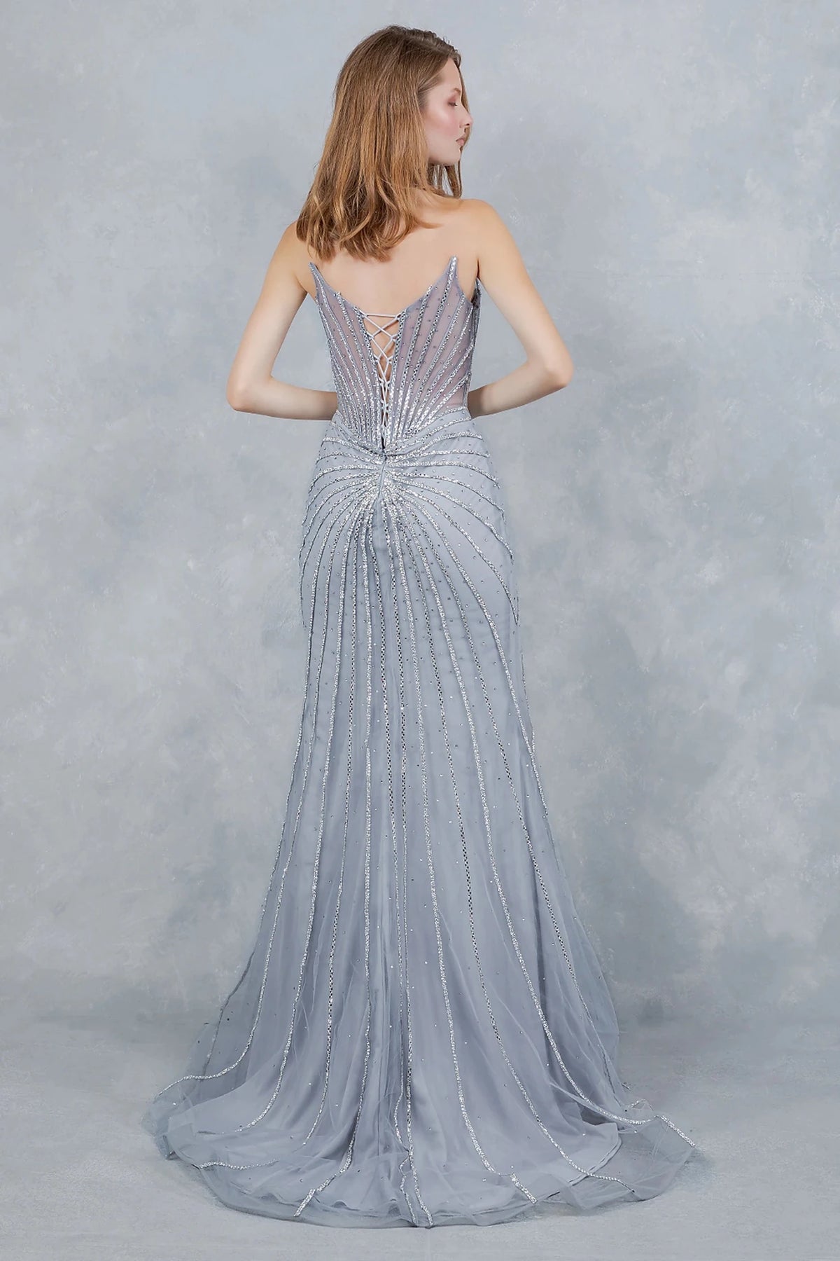 Silver evening gown showcasing sunburst pattern extending across structured bodice and lace back up