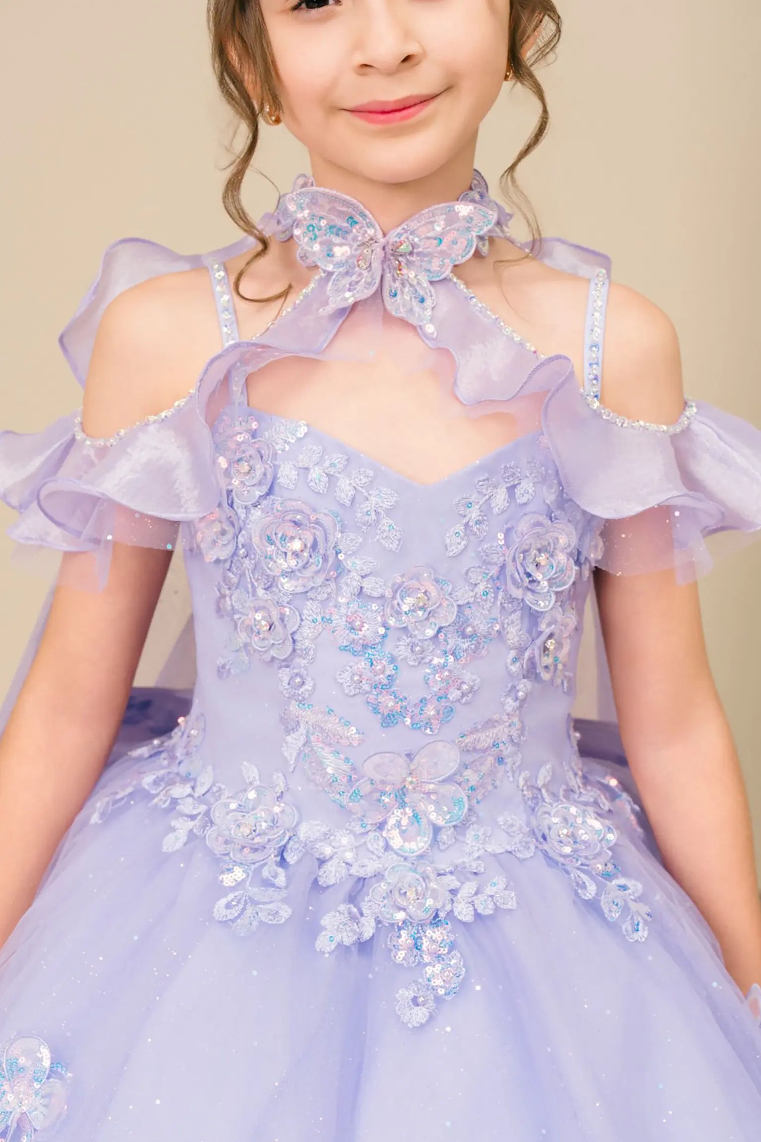 Bodice close-up of a kid wearing lilac mini quinceañera dress showing floral appliques, butterfly collar detail, and subtle glitter accents.