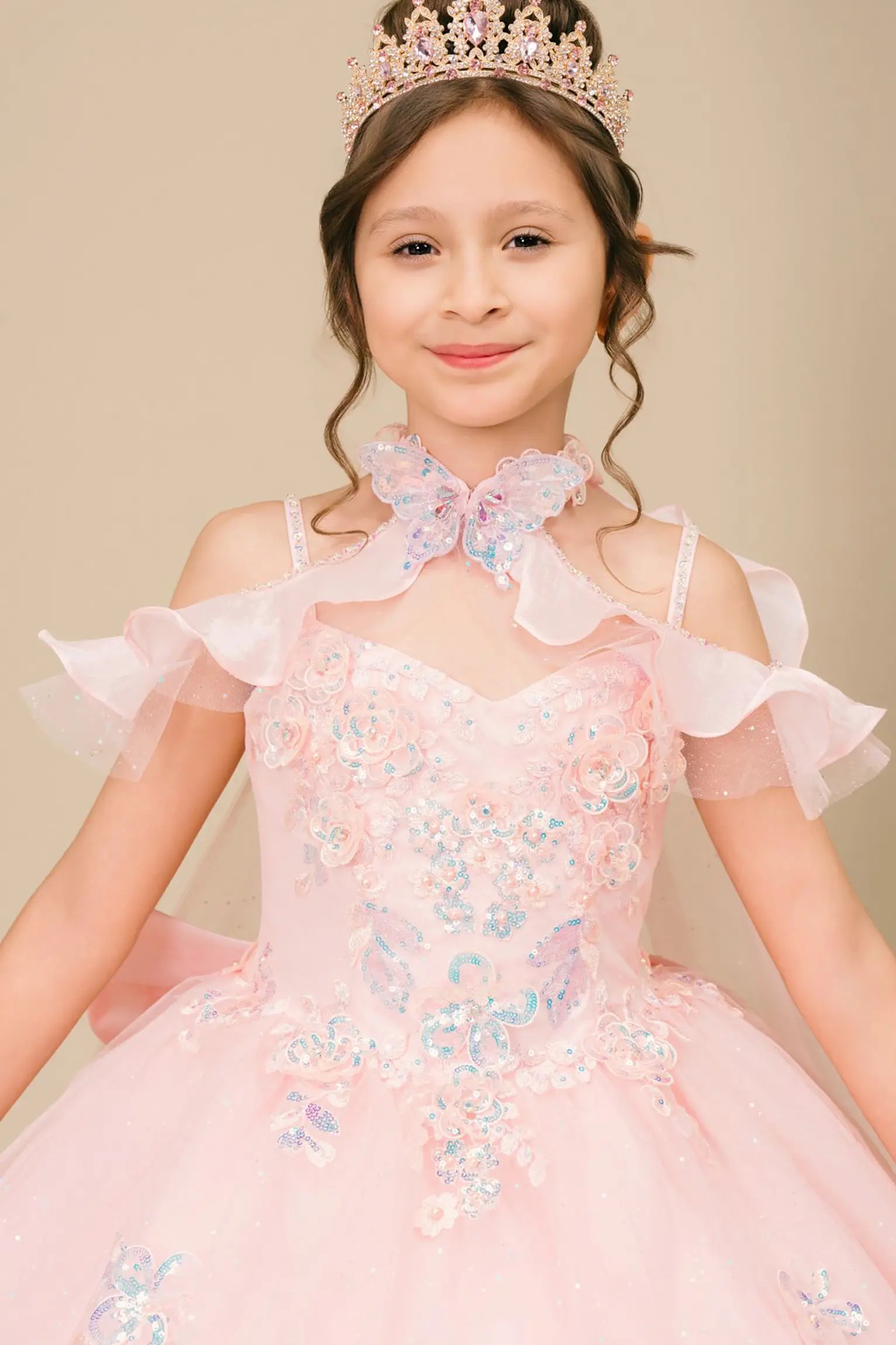 Bodice back close-up of a woman wearing pink mini quinceañera dress showing floral appliques, butterfly collar detail, and glitter accents.
