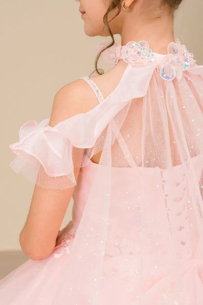 Close Up back view of a woman wearing pink mini quinceañera dress with voluminous tulle skirt, lace-up corset closure, and floral appliques trailing across the bodice.