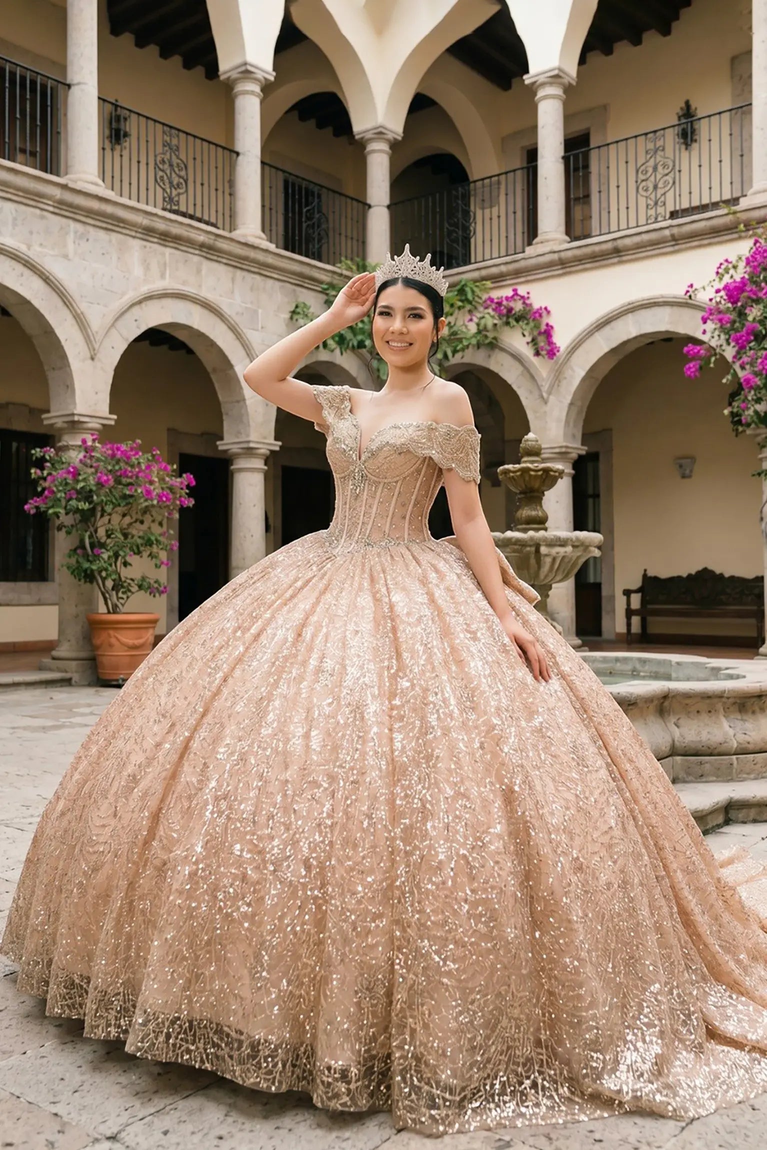 Full front view of a woman wearing rose gold quinceañera dress with sparkly tulle skirt, off-shoulder ruffles, and beaded corset bodice.