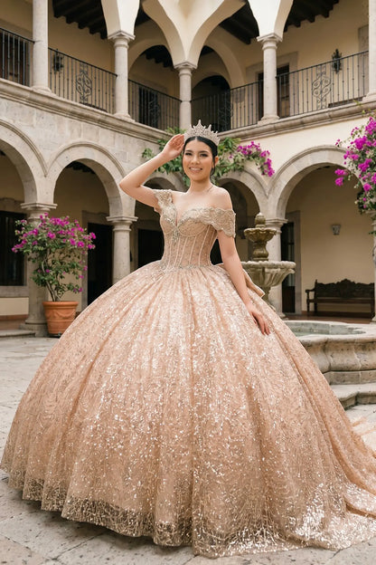 Full front view of a woman wearing rose gold quinceañera dress with sparkly tulle skirt, off-shoulder ruffles, and beaded corset bodice.