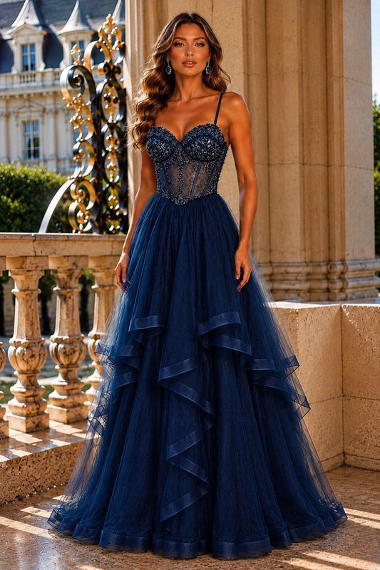 Shown in a front view, the Navy prom and evening dress has beaded bodice and layered tulle ruffle skirt.