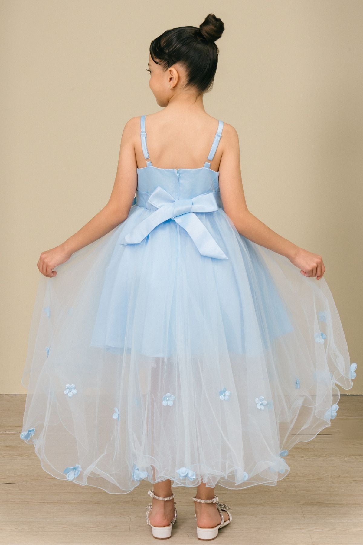 Back view of sky blue high-low tulle flower girl dress with lace-up bodice, 3D floral appliqué accents, and flowing high-low skirt.