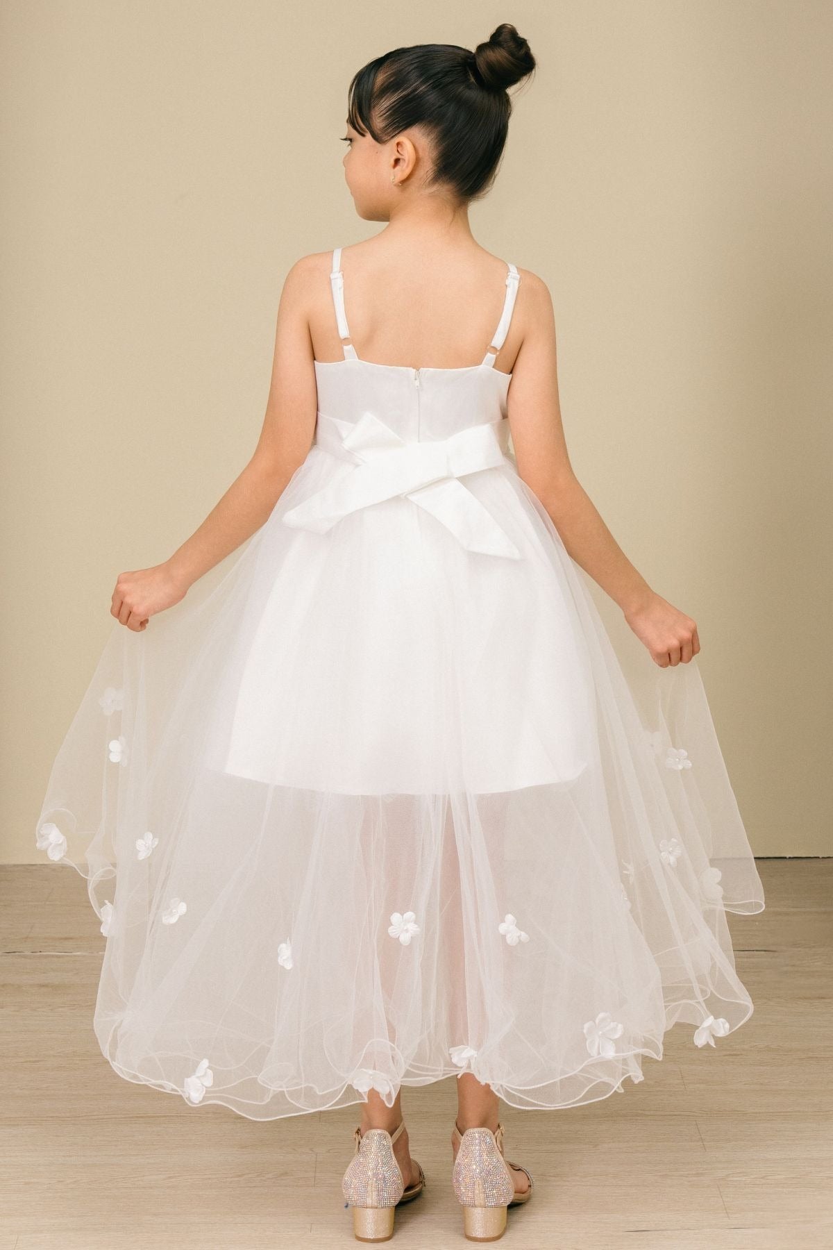 Back view of white high-low tulle flower girl dress with lace-up bodice, 3D floral appliqué accents, and dramatic high-low skirt.