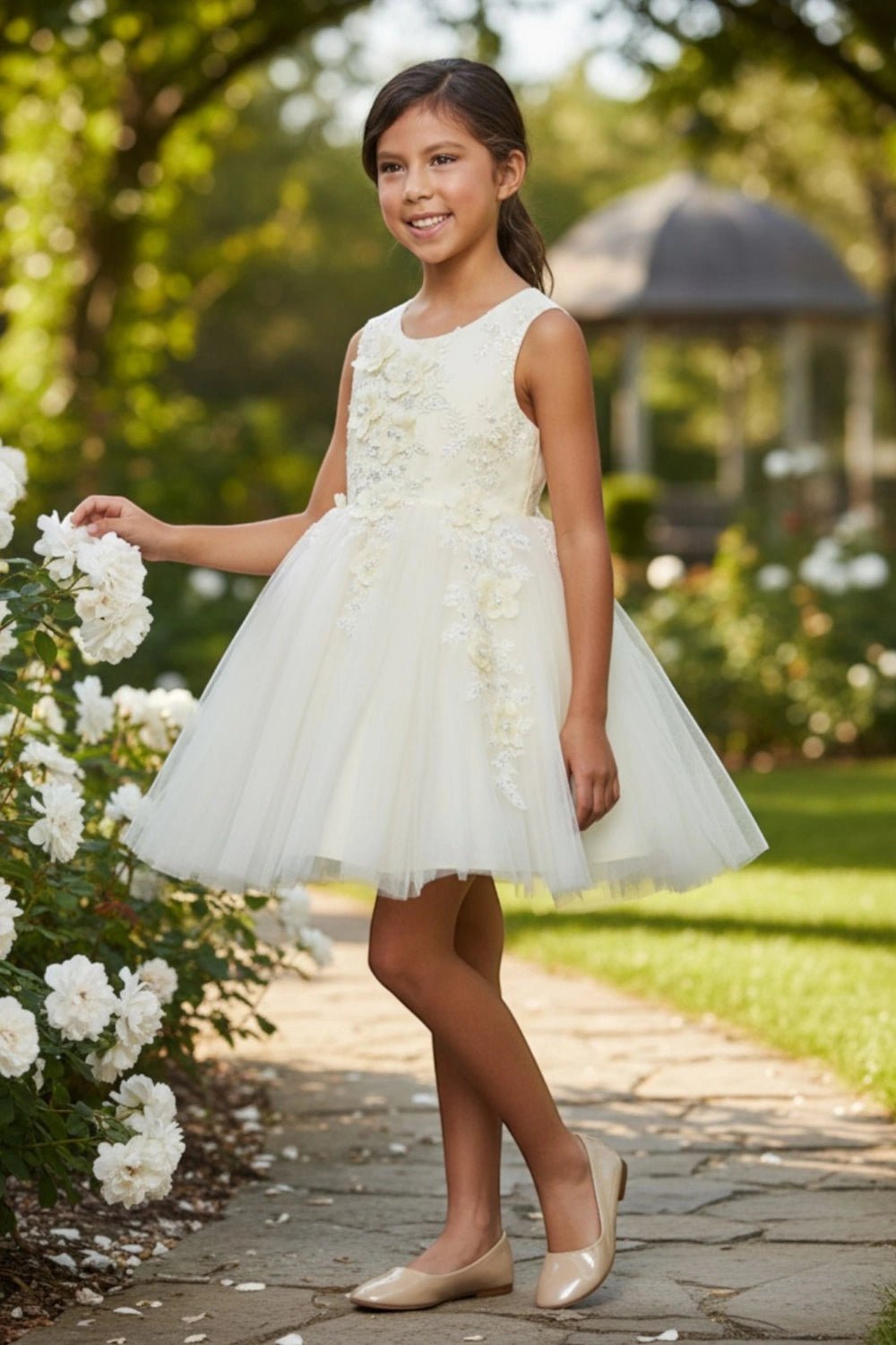 Shown in a front view, the Champagne flower girl dress has sleeveless floral bodice and short full tulle skirt.