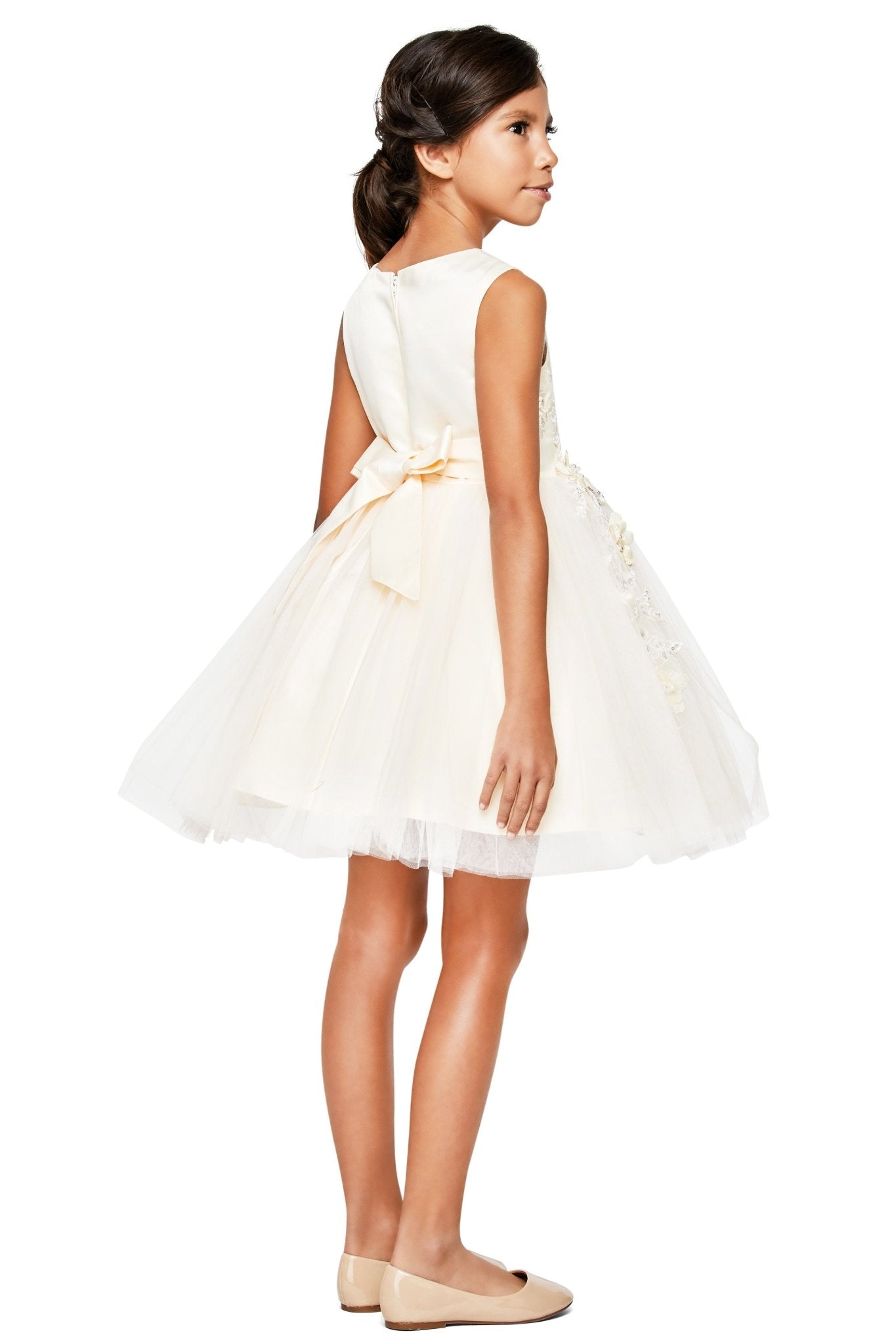Back view of champagne sleeveless flower girl dress with lace-up bodice, 3D floral appliqué accents, and wired tulle skirt.