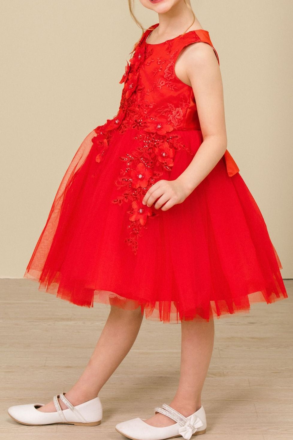 Side view of red sleeveless flower girl dress with 3D floral appliqué detailing and voluminous wired tulle skirt.