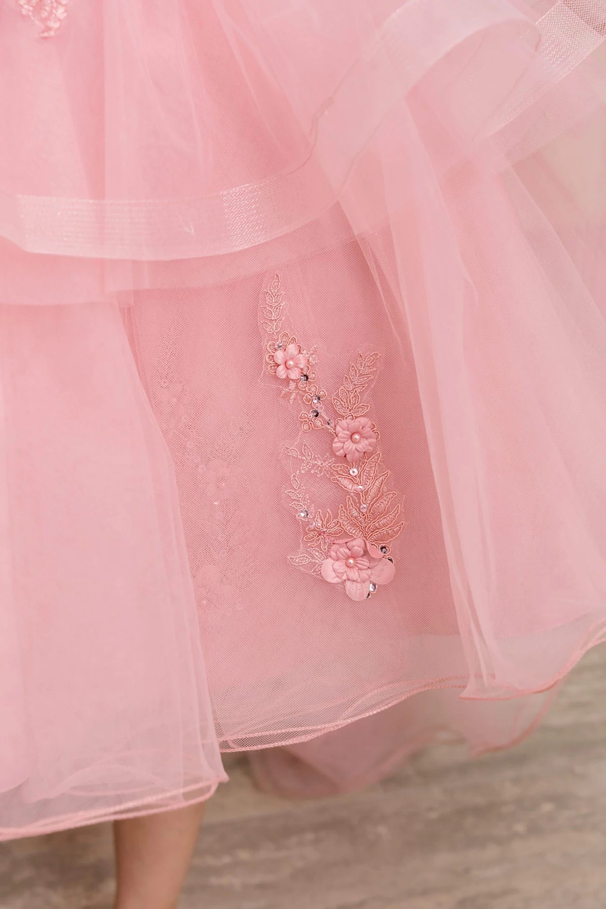 Close-up of a dusty rose flower girl dress with floral embroidery.