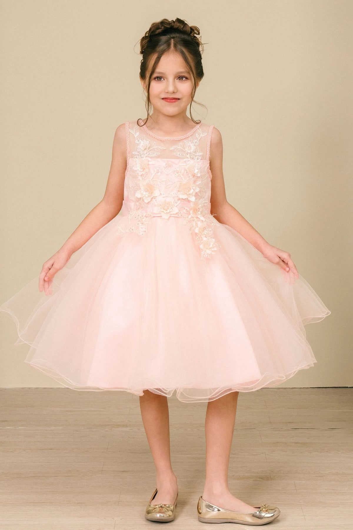 Peach flower girl dress features flower appliques and a flared tulle skirt.