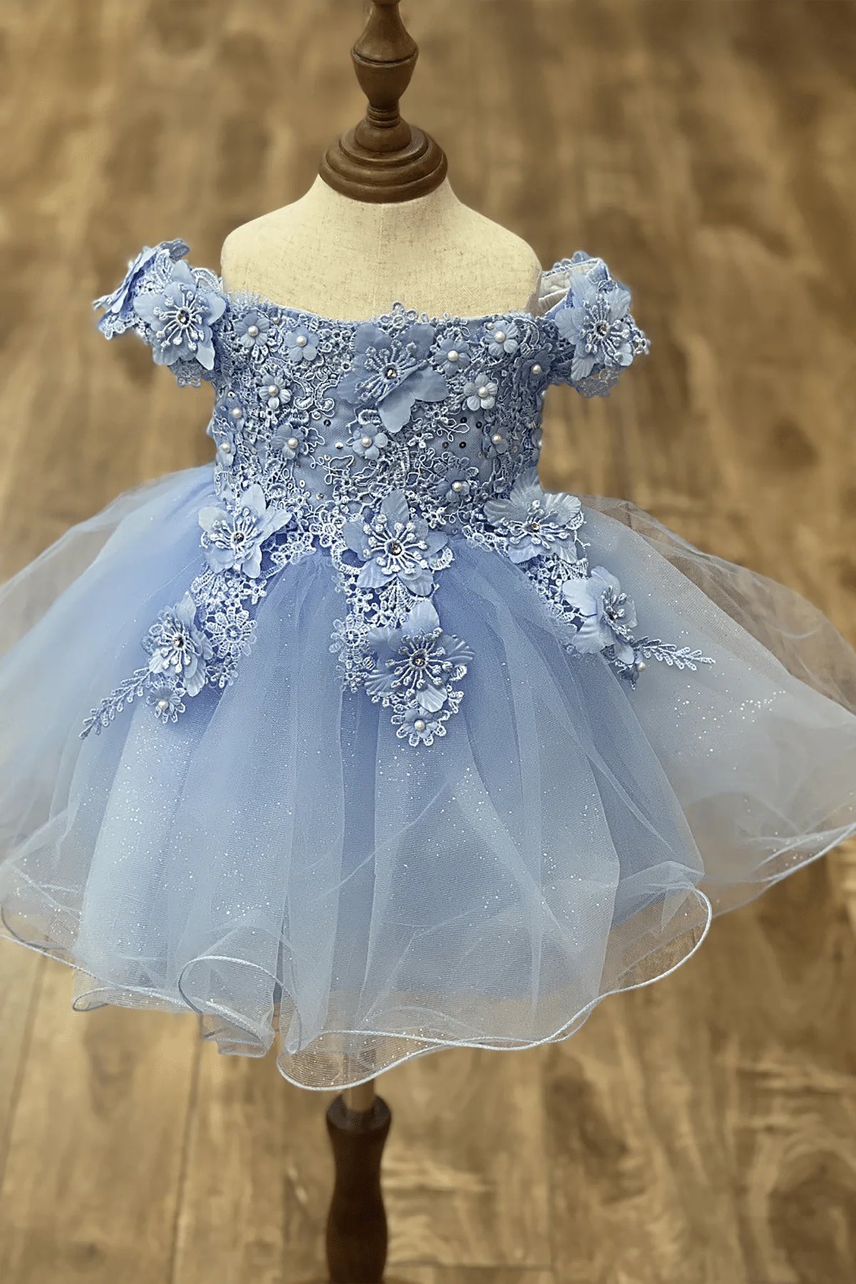Sky blue off-the-shoulder flower girl dress with 3D floral appliqué bodice, rhinestone embellishments, and glitter tulle layered skirt.