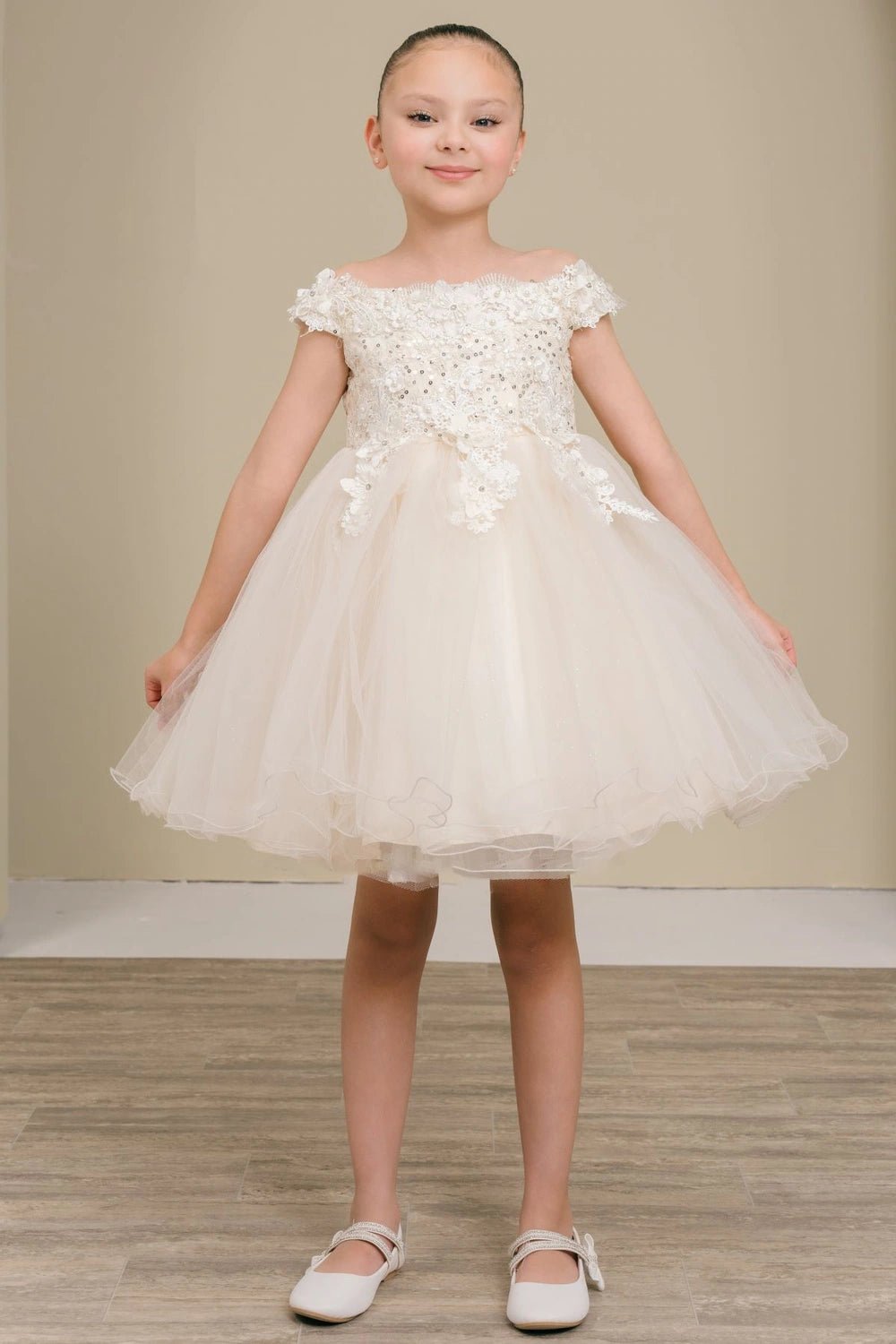 Shown in a front view, the Champagne flower girl dress has off-shoulder floral neckline and full glitter tulle skirt.
